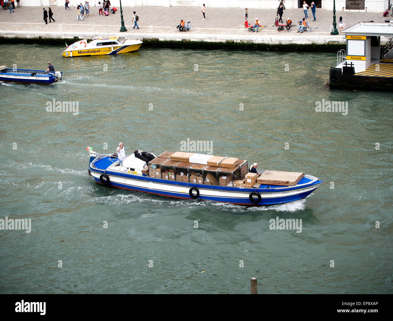 Un commerciale blu barca caricata di beni sul Canal Grande a Venezia Foto Stock