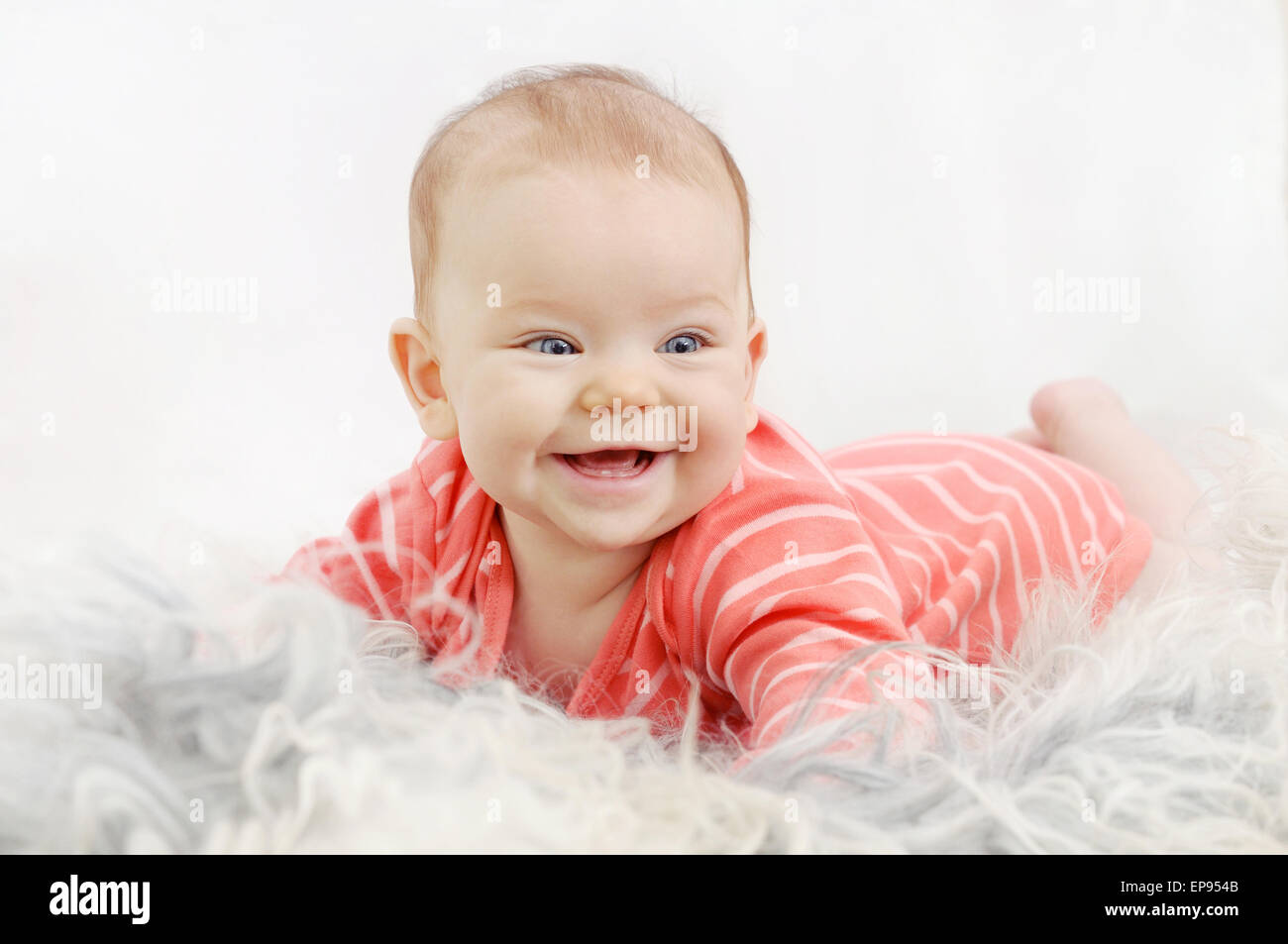 Molto felice carino bambina con un ampio sorriso sul divano bianco Foto Stock