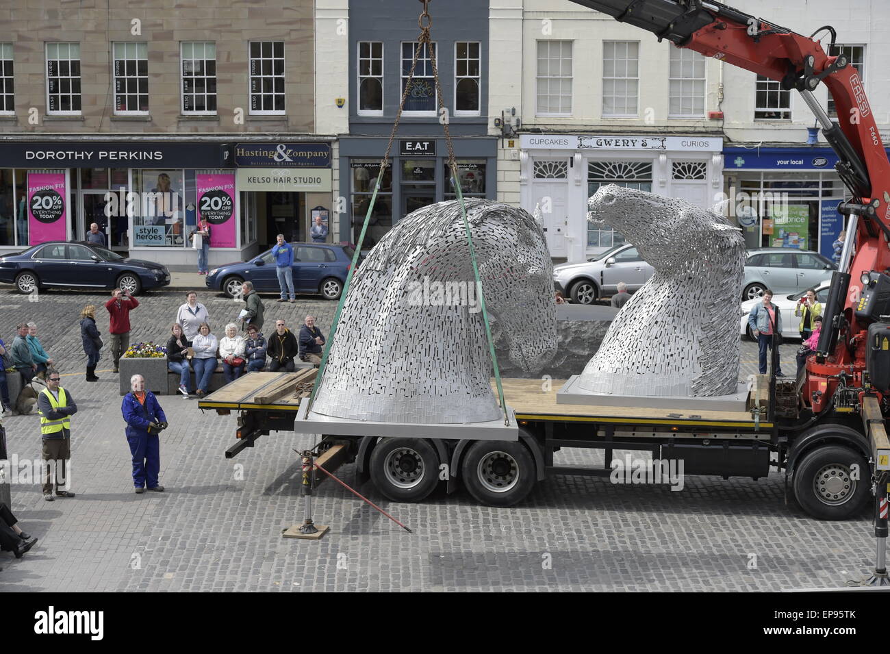 Kelso, Scotland, Regno Unito. Il 15 maggio 2015 tre metri Kelpies elevata per essere stabulati in Kelso quadrato di un decimo di scala touring Kelpies sculture di arrivare in piazza a Kelso venerdì 15 maggio, con studenti locali da Broomlands e Edenside scuole primarie accogliente il loro arrivo. L'iconico sculture rimarrà in posizione al centro della città fino a lunedì 18 maggio. Ciò coincide con un weekend intenso in città e con il castello di pavimenti Horse Trials e la frontiera Vintage associazione agricola annuale del rally a Springwood Park di prendere posto. Credito: Rob grigio/Alamy Live News Foto Stock