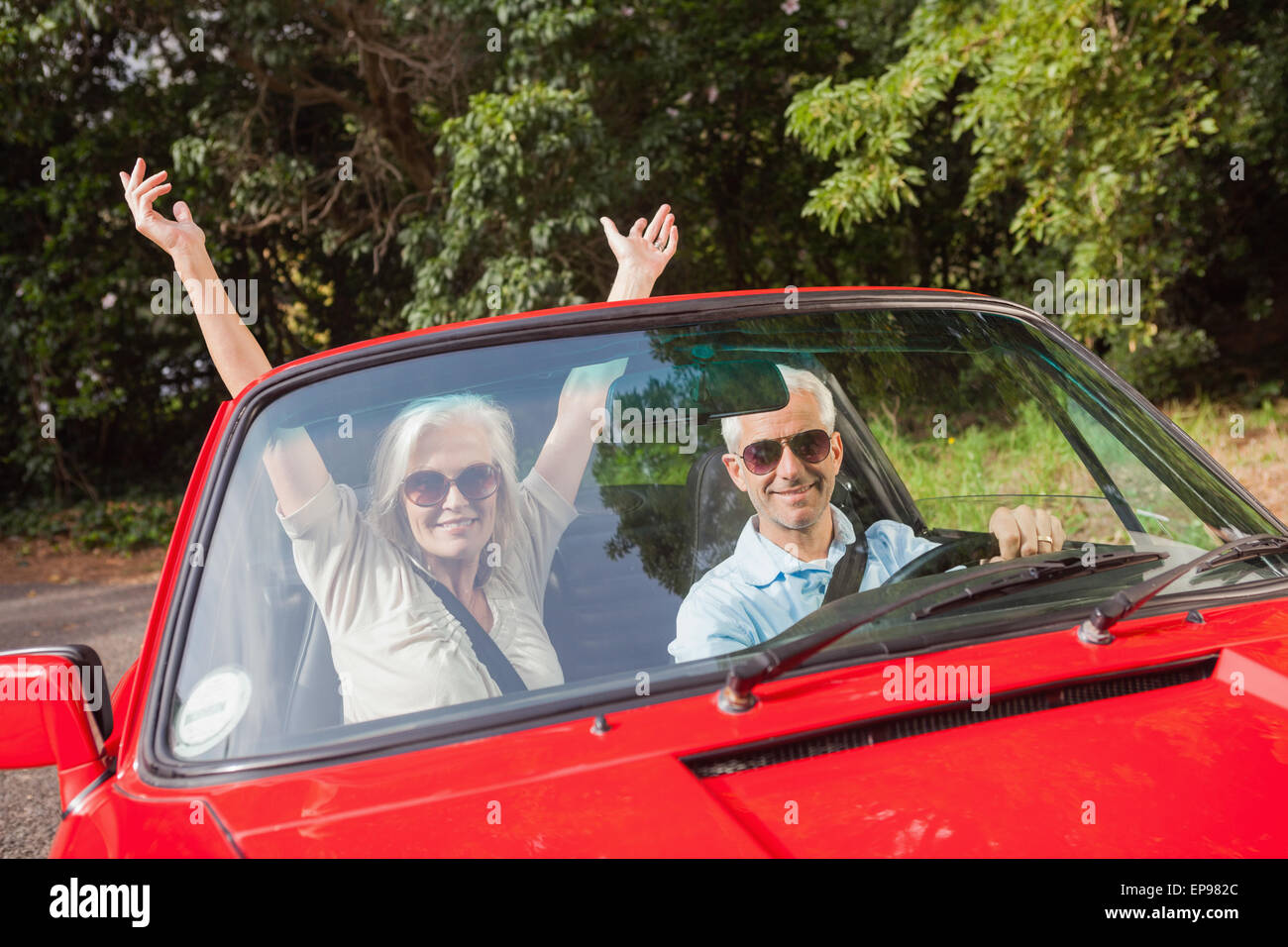 Coppia matura in rosso cabriolet tifo in telecamera Foto Stock