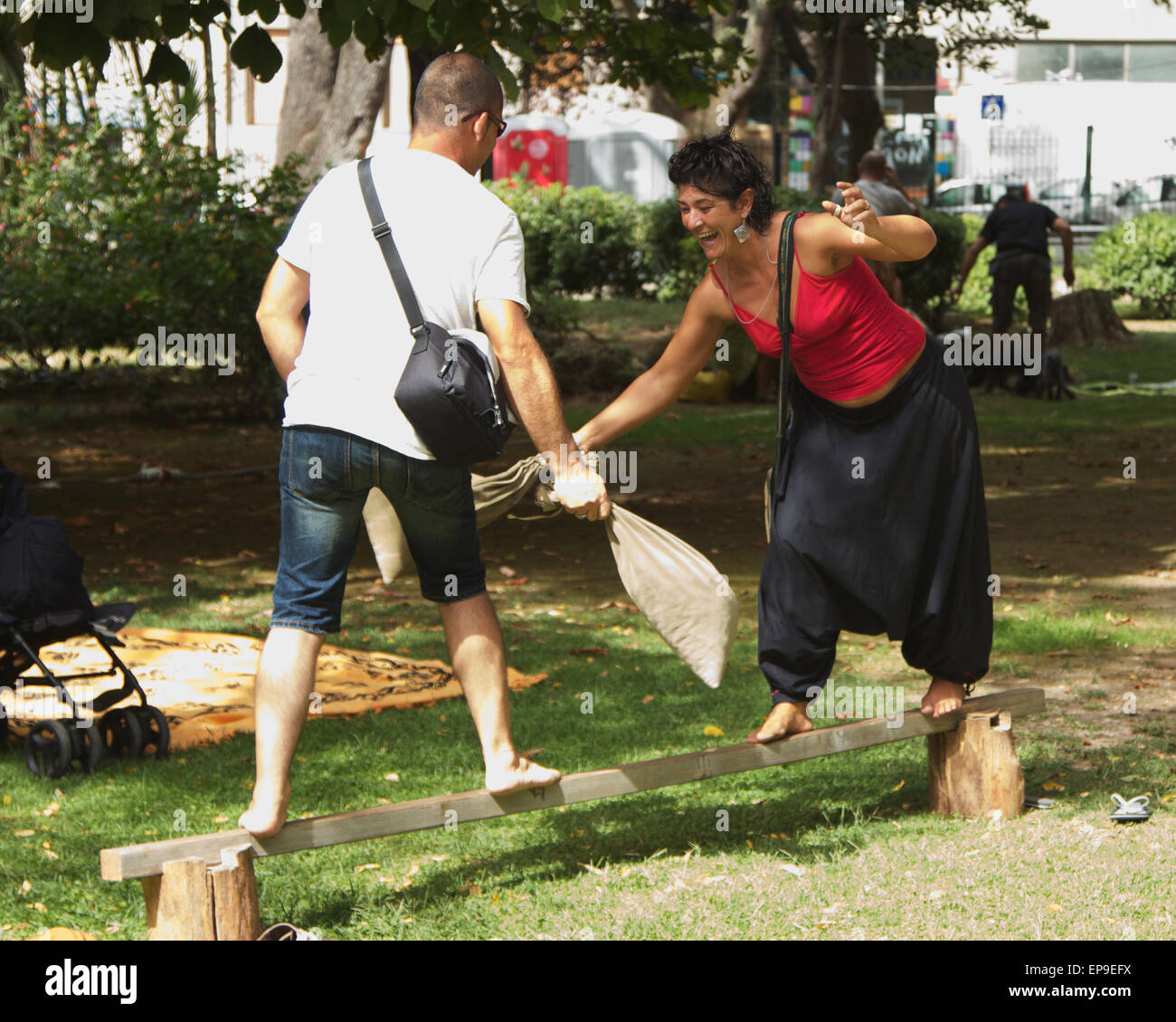 Un uomo e una donna in equilibrio su un palo di legno cercando di knock ogni altro off con sacchi di sabbia Foto Stock