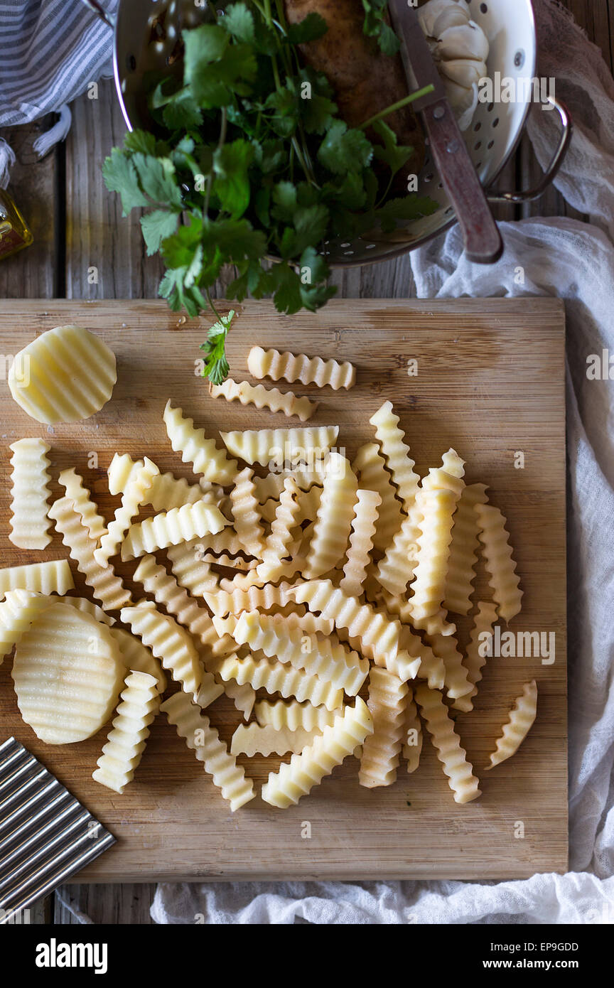 Patate tagliate con un coltello crinckle visualizzata su un tagliere. Foto Stock