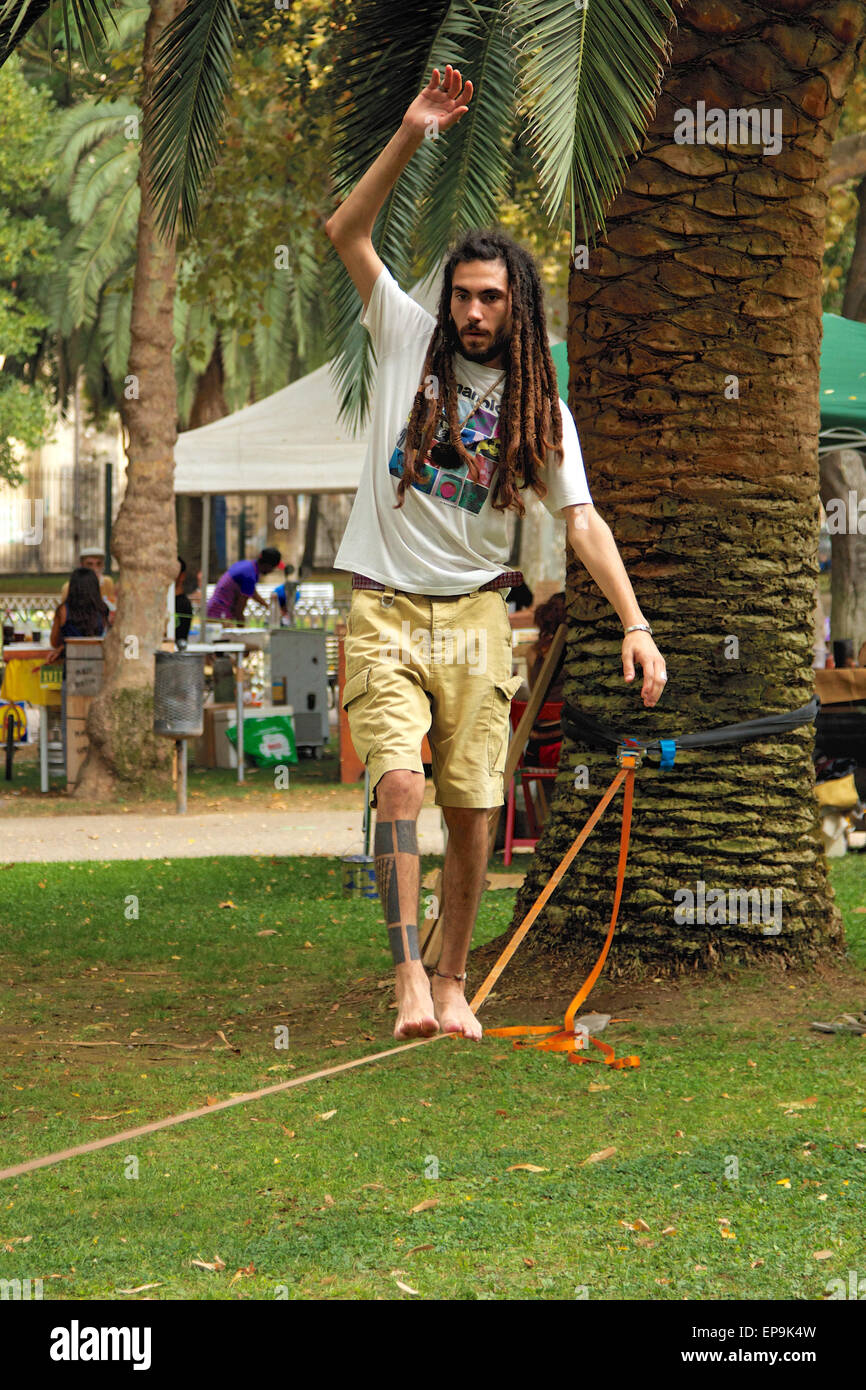 Uomo con dreadlocks e tatuaggi in equilibrio su una fune Foto Stock