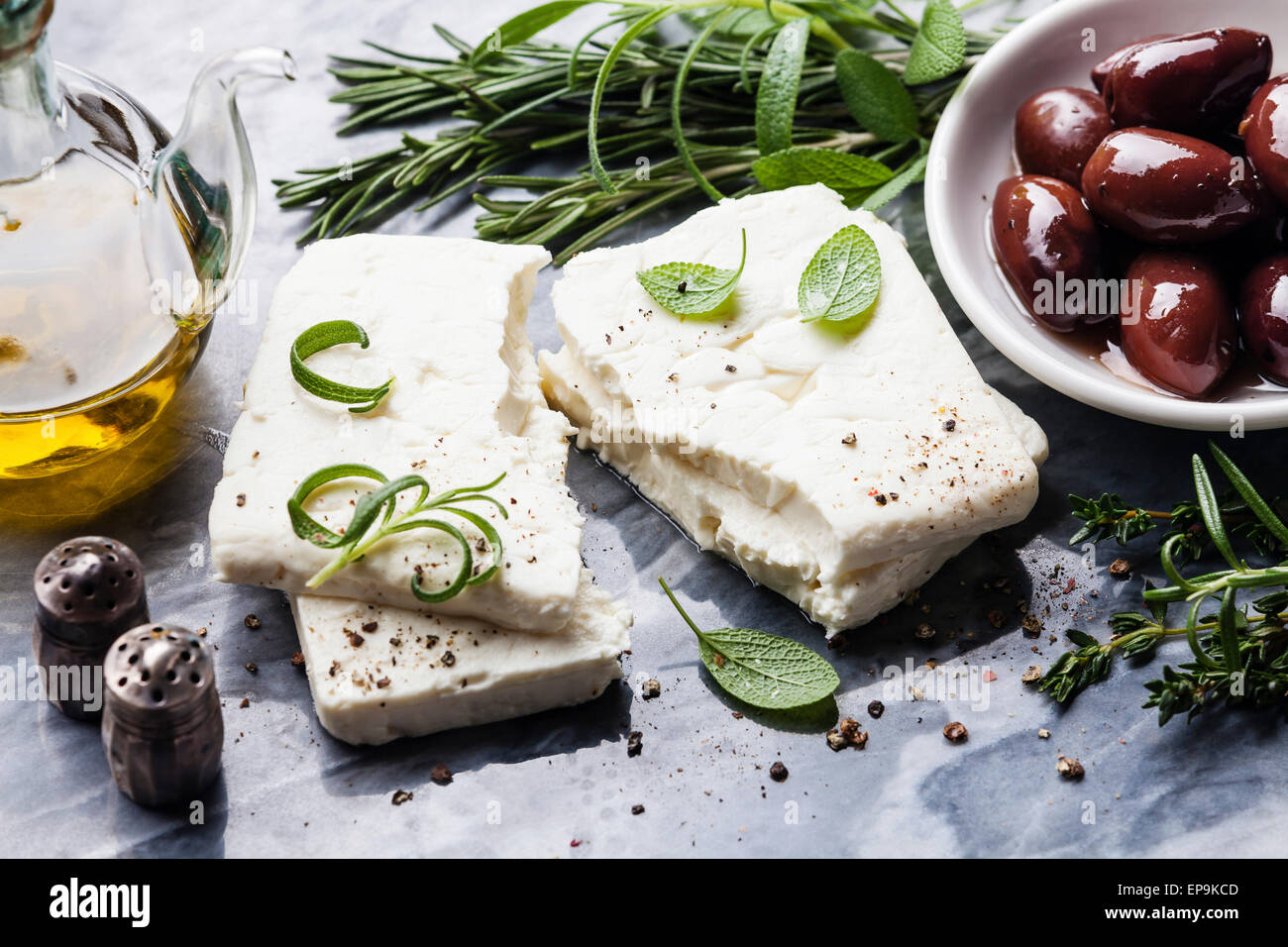 Il formaggio Feta con olive nere e verdi di erbe su grigio Sfondo marmo Foto Stock