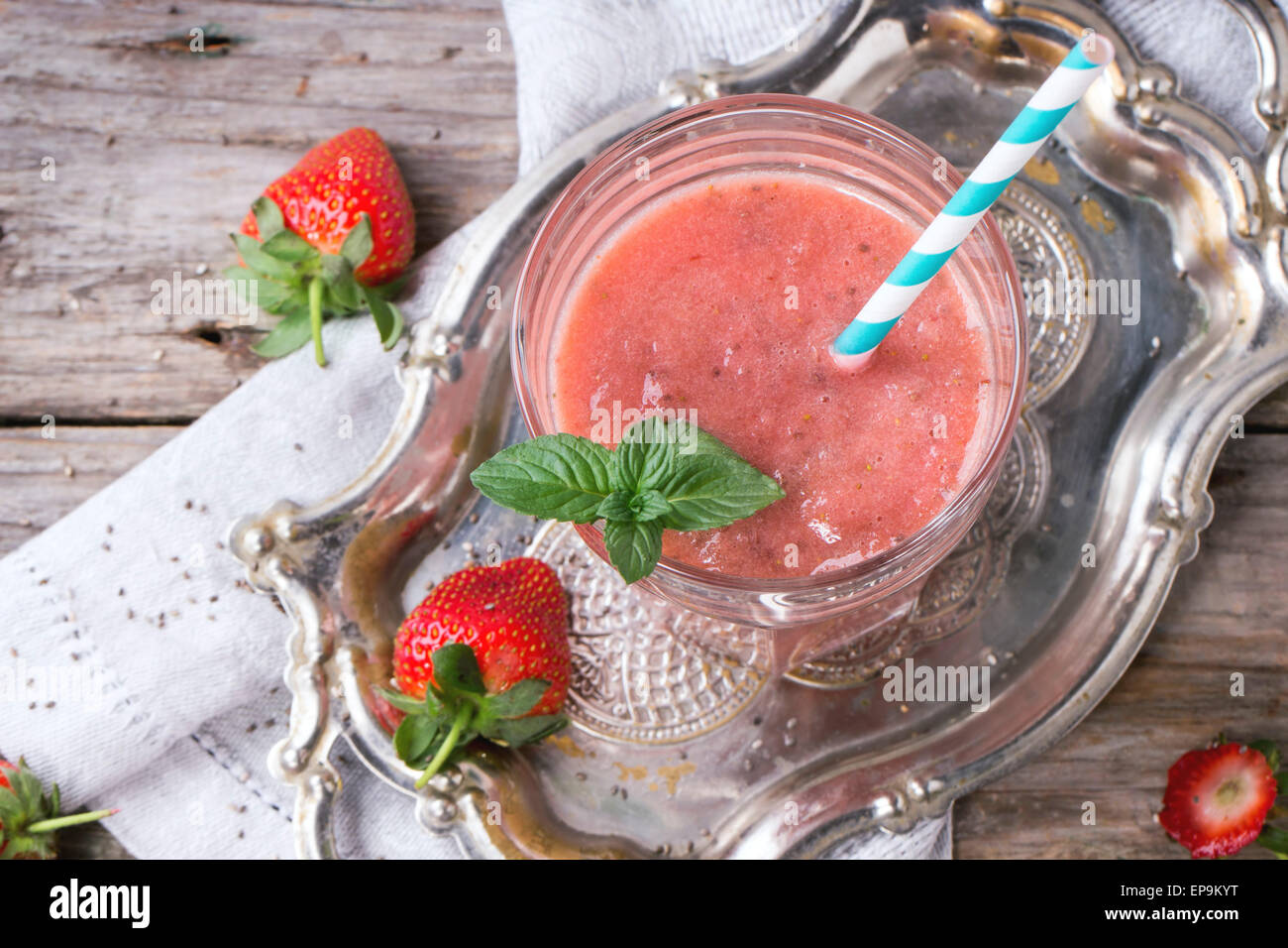 Bicchiere di rosso frullato fragole con semi di Chia, serviti con cocktail retrò, tubo di menta fresca e fragole su un tavolo di legno Foto Stock