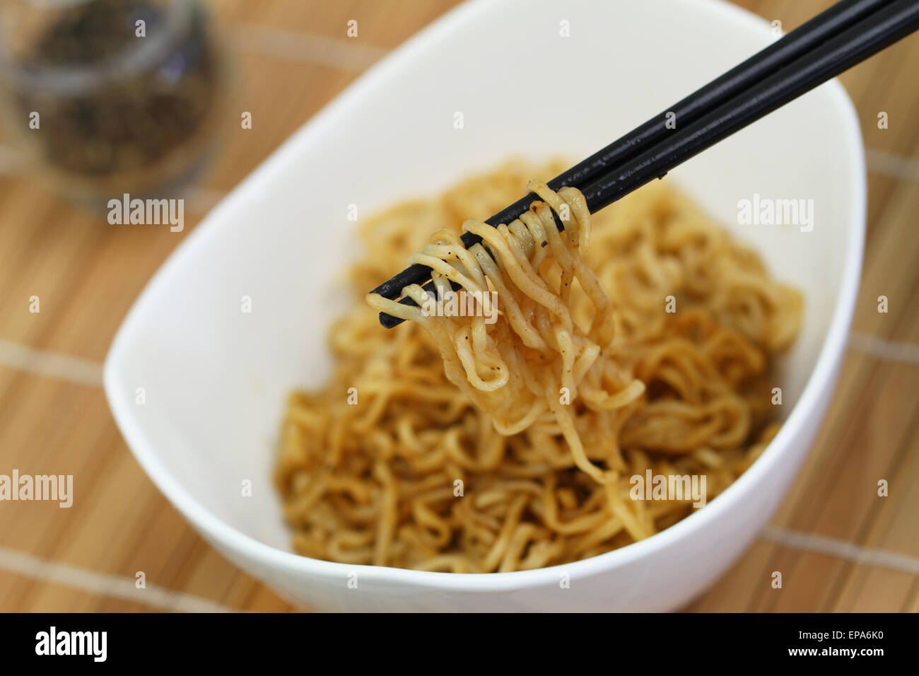Spaghetti Cinesi in un recipiente e bacchette sul tappetino di bambù Foto Stock