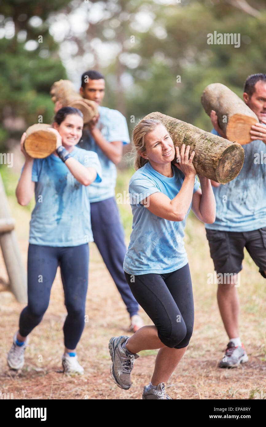 Le persone che eseguono log boot camp ostacolo corso Foto Stock
