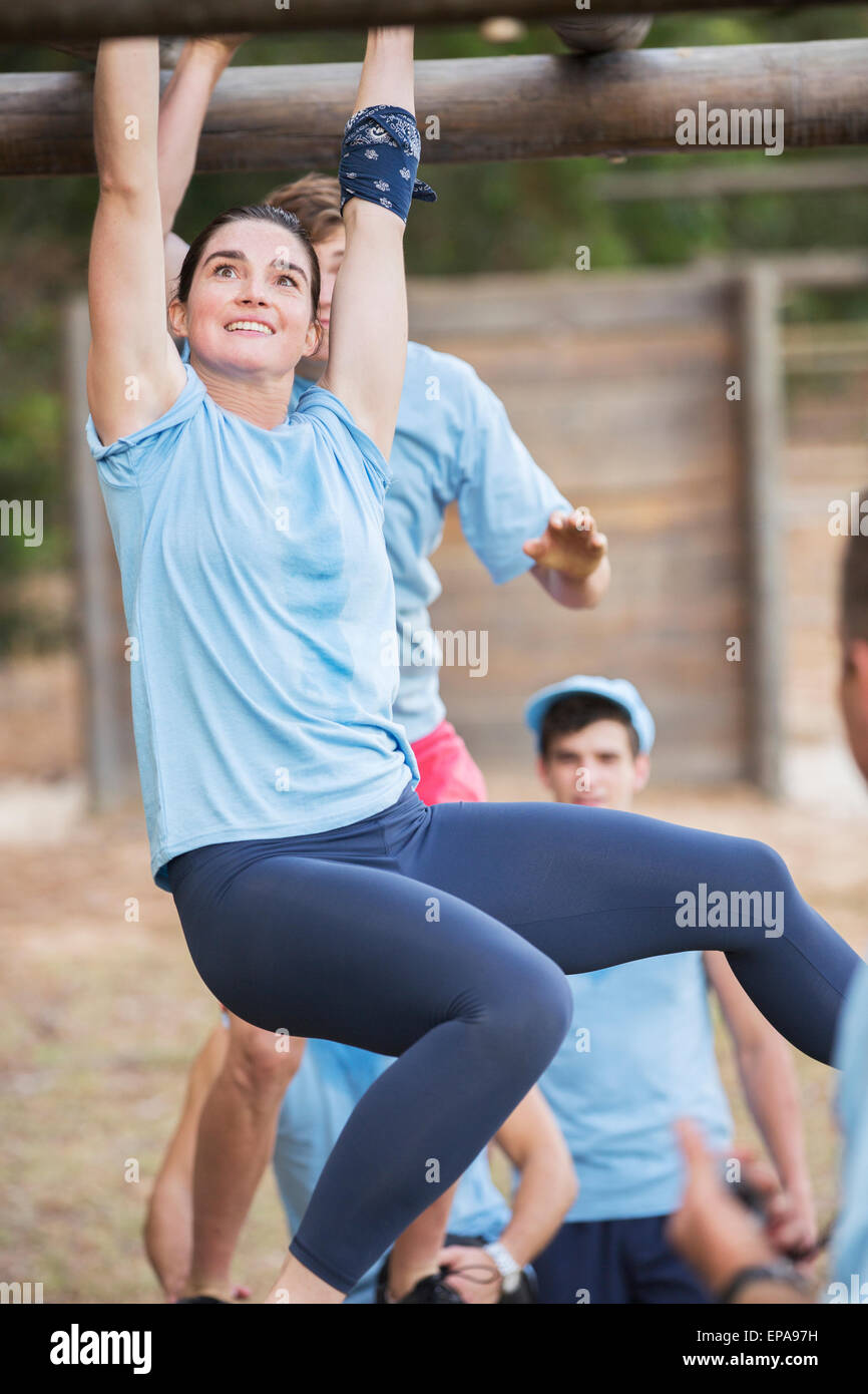 Donna sorridente attraversando Monkey bar boot camp Foto Stock