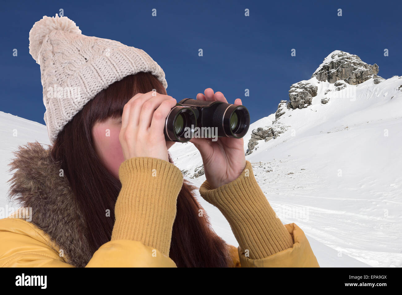 Junge Frau schaut in den Bergen durch ein Fernglas Foto Stock