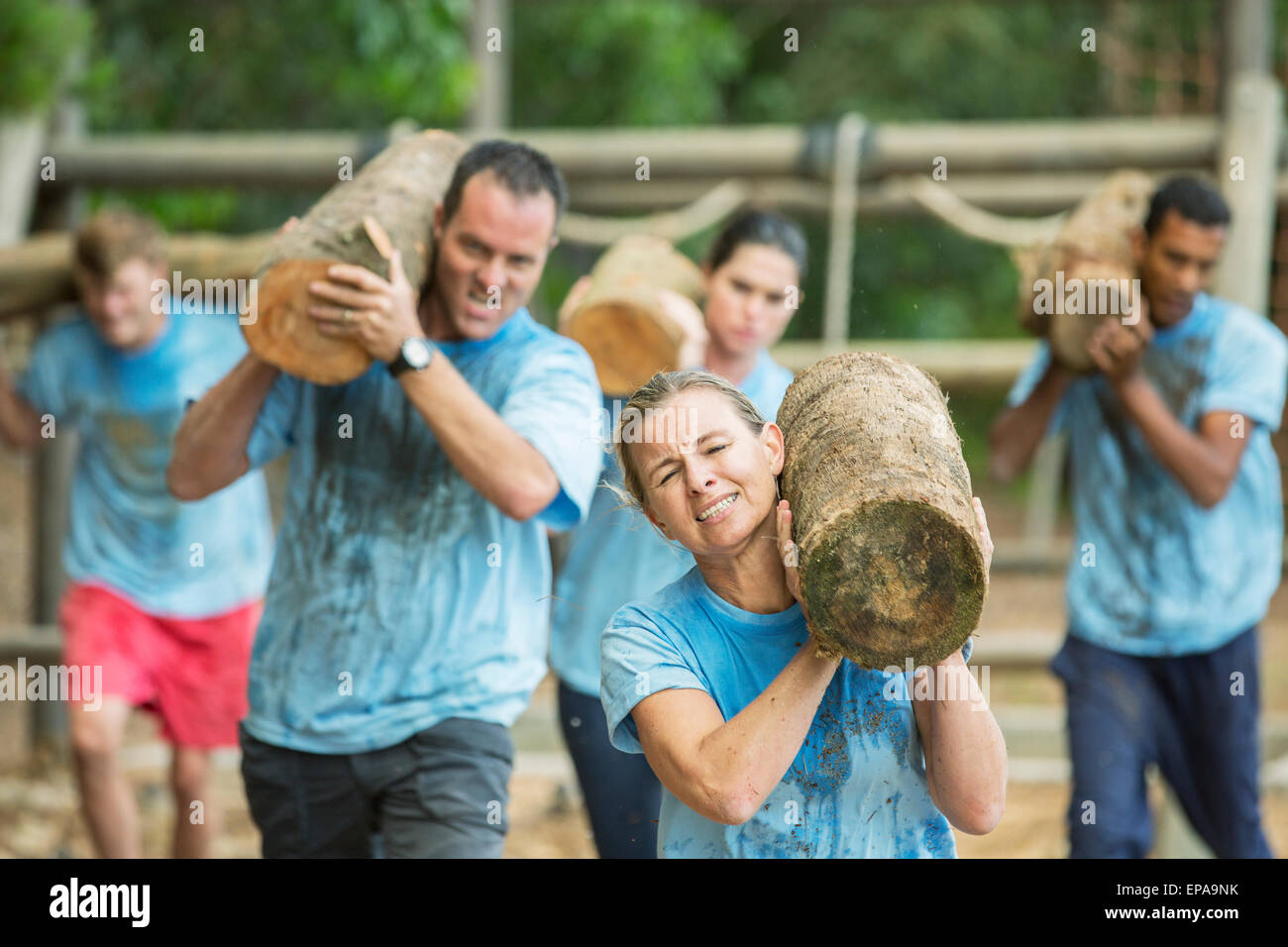 Le persone che eseguono log boot camp ostacolo corso Foto Stock