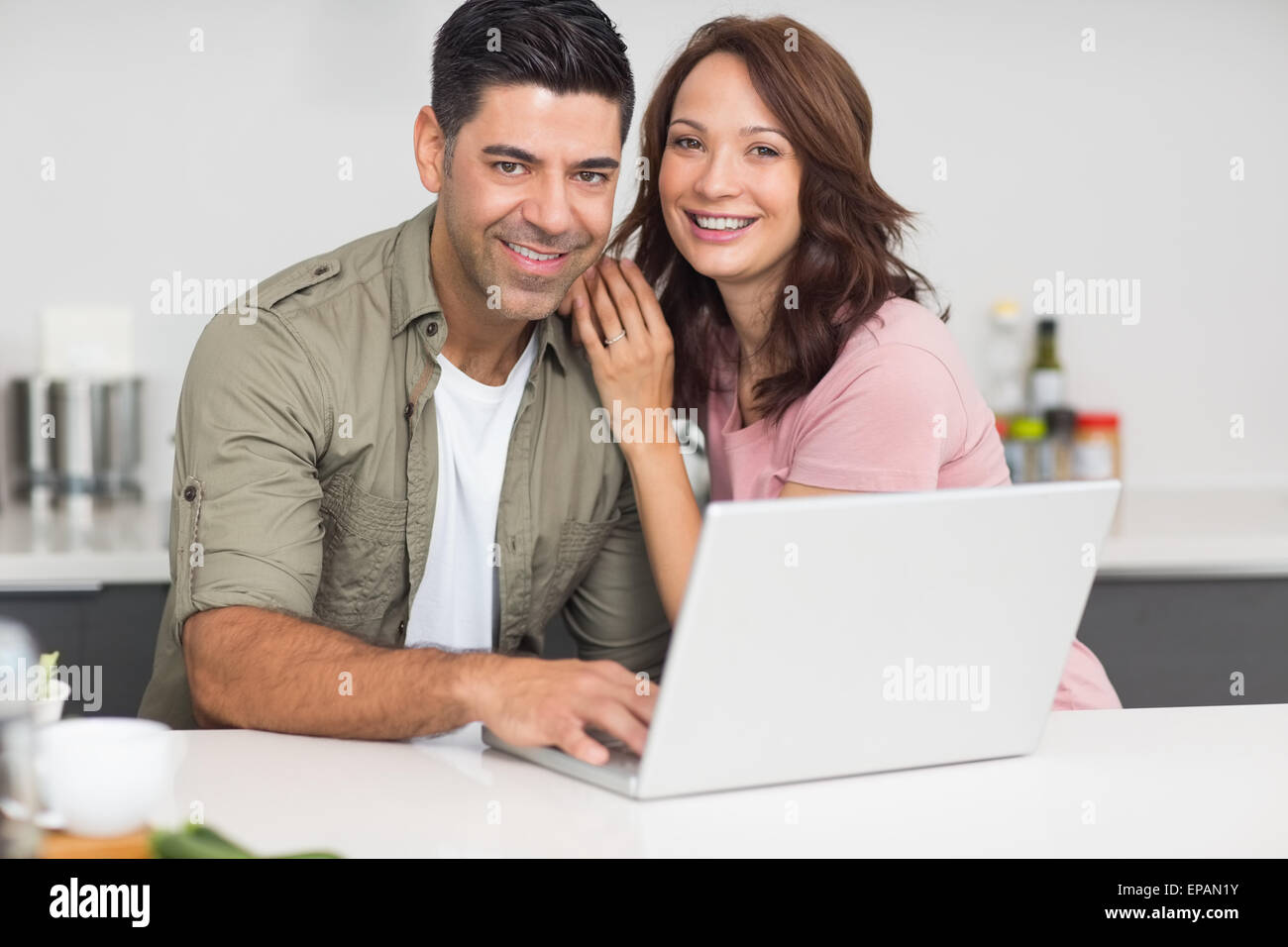 Ritratto di una coppia felice utilizzando laptop in cucina Foto Stock