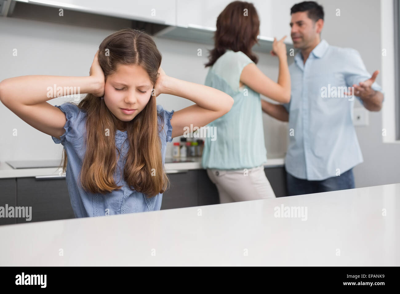 Ragazza triste che copre le orecchie mentre i genitori quarreling in cucina Foto Stock