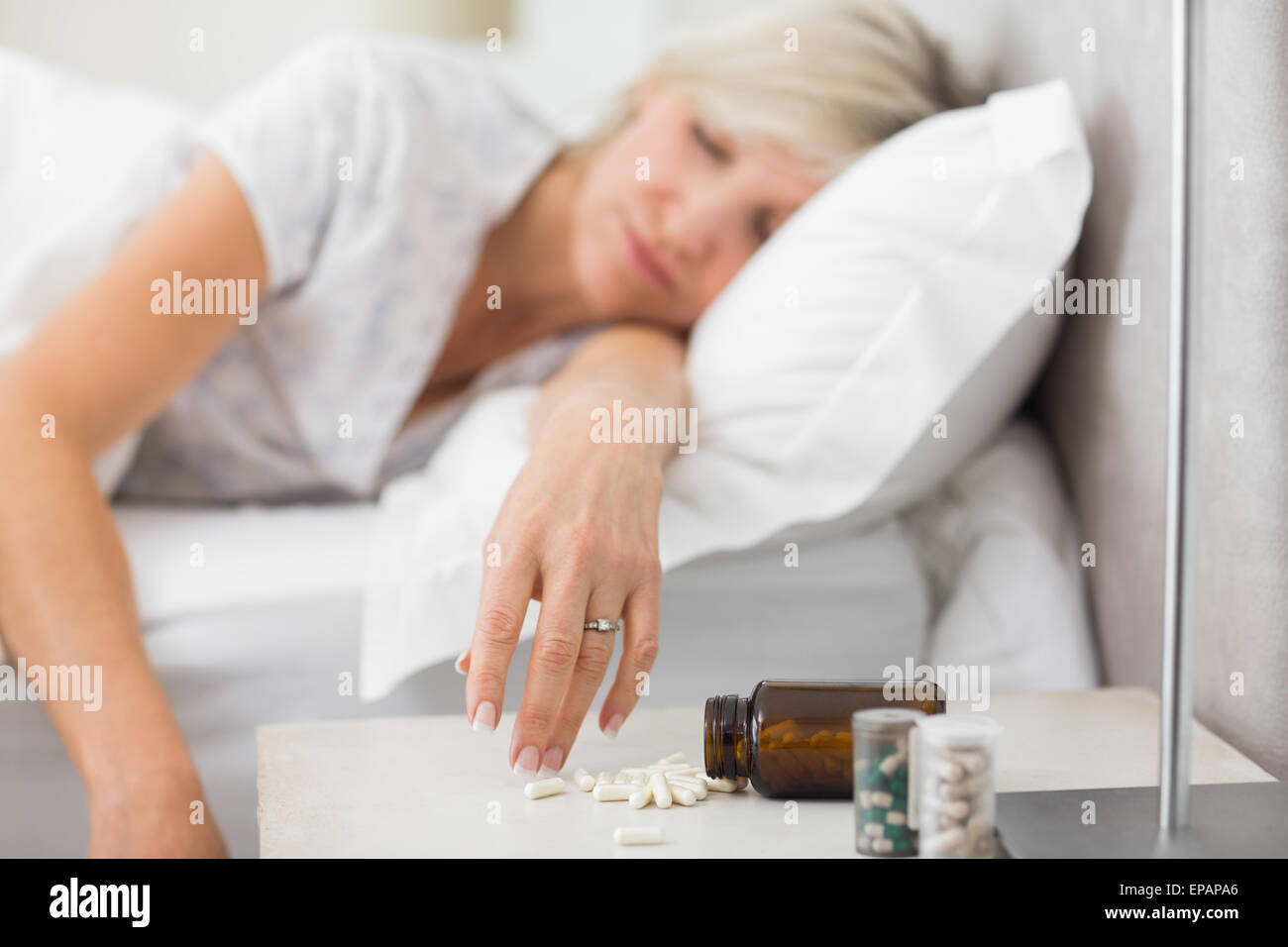 Donna che dorme nel letto con le pillole in primo piano Foto Stock