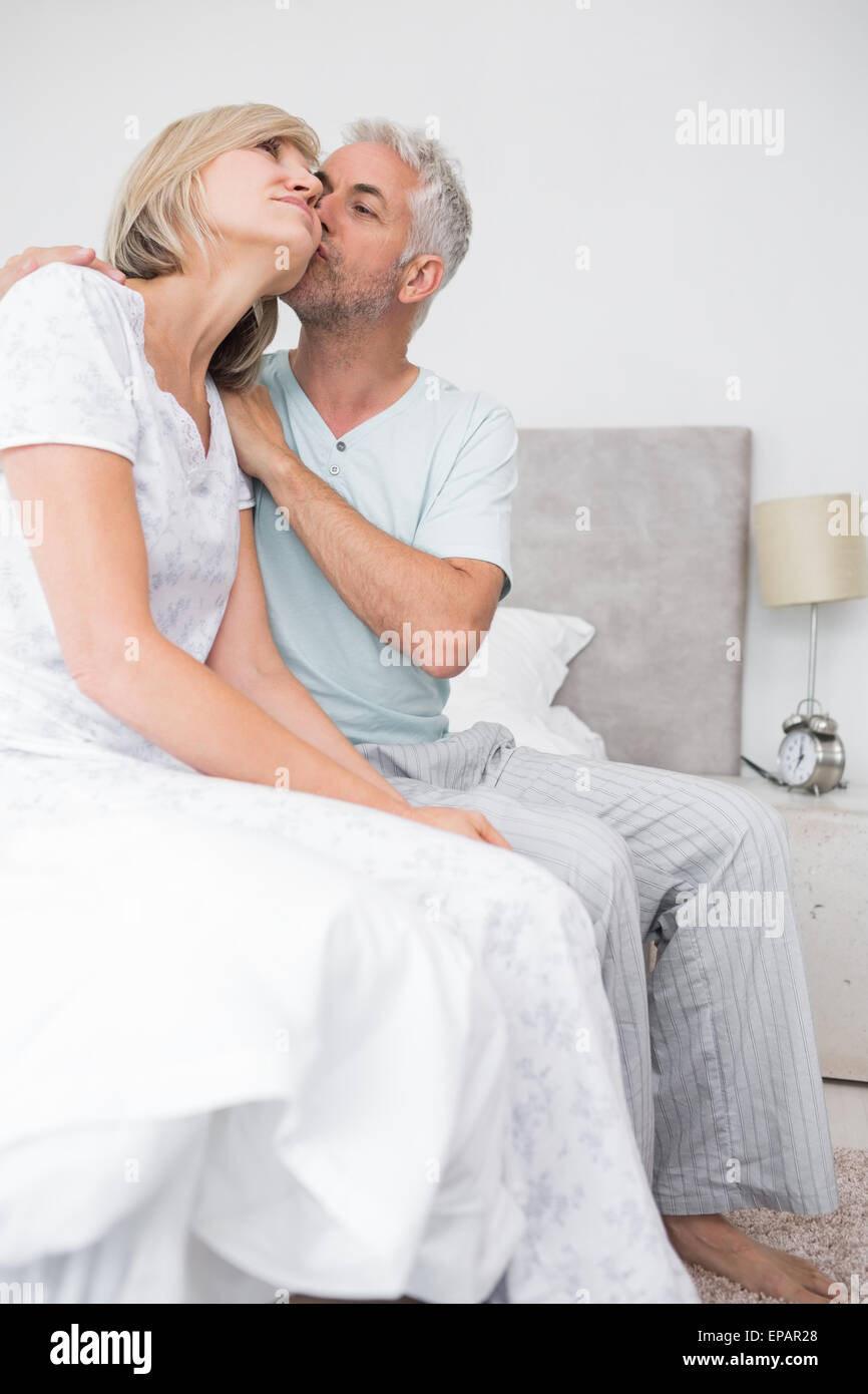 Uomo maturo kissing womans guancia a letto Foto Stock