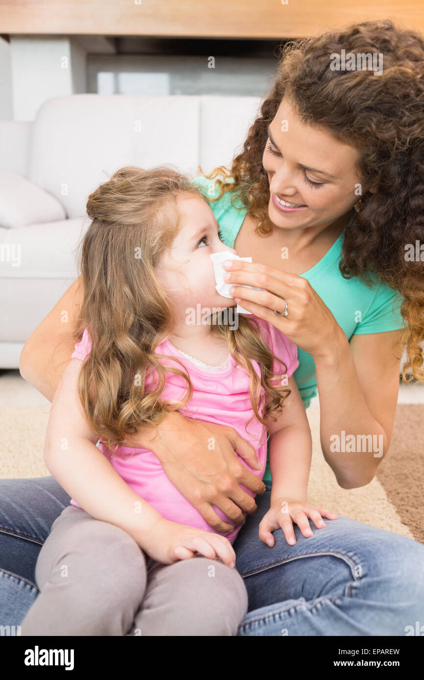 Madre aiutare la sua piccola figlia soffiare il naso Foto Stock