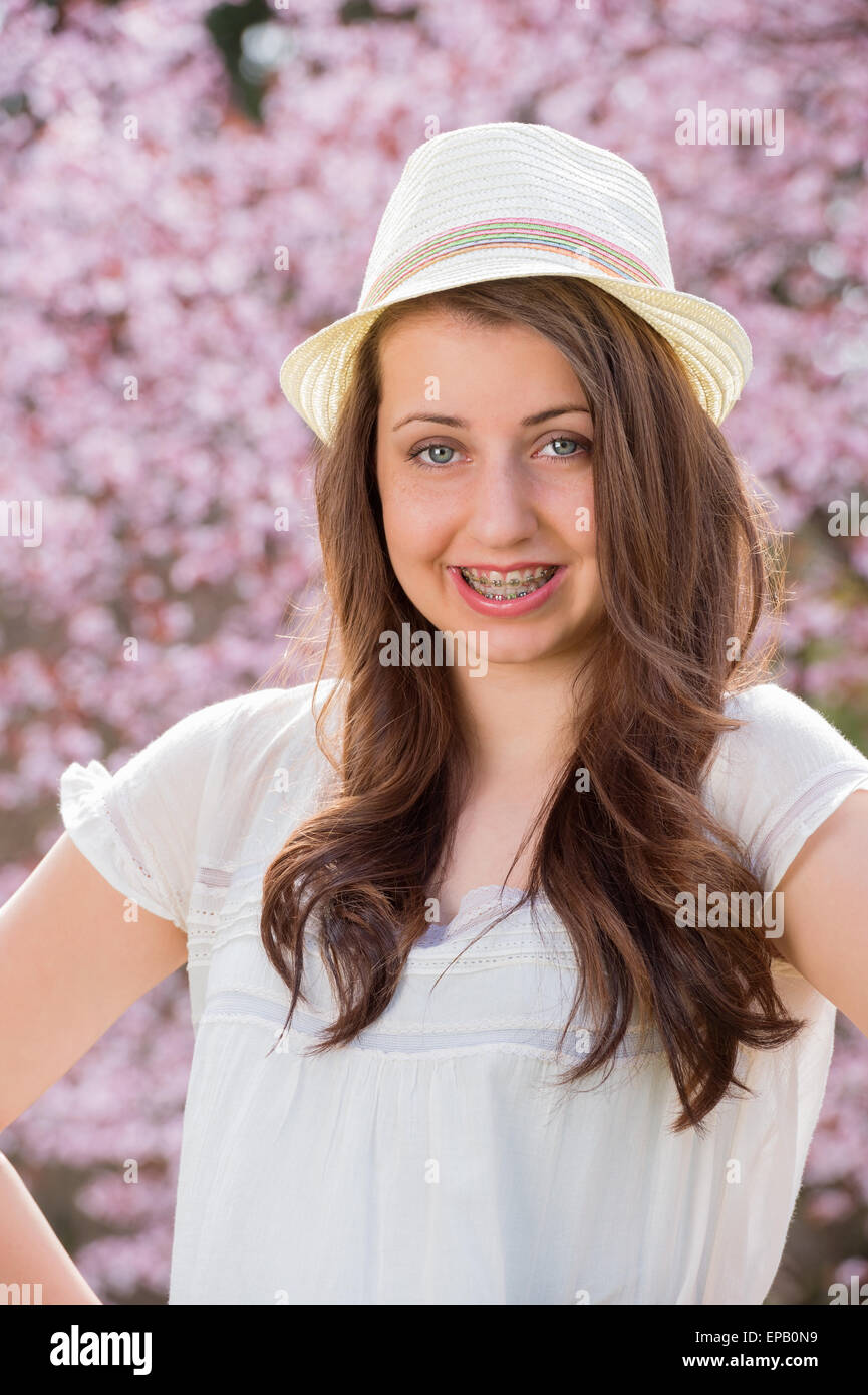 Ragazza con bretelle indossando hat primavera sbocciano i fiori Foto Stock
