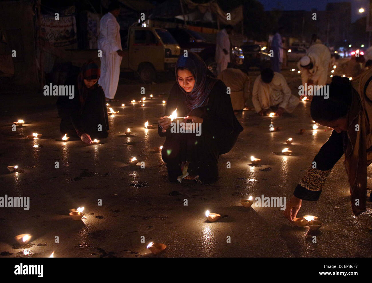 Membri della Lega musulmana-Q sono in terracotta di alleggerimento lampada durante una manifestazione contro il massacro di persone che appartengono alla Comunità Ismaili che hanno assassinato da uomini armati non identificati, al di fuori di Karachi press club del venerdì, 15 maggio 2015. Foto Stock