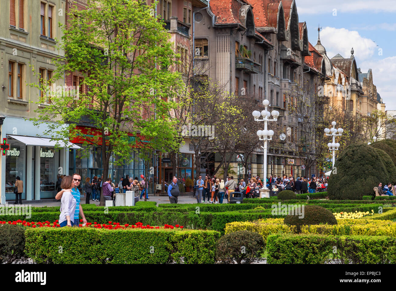 I pedoni a piedi attraverso i giardini di piazza della Vittoria o Piata Victoriei in Timisoara ROMANIA Foto Stock