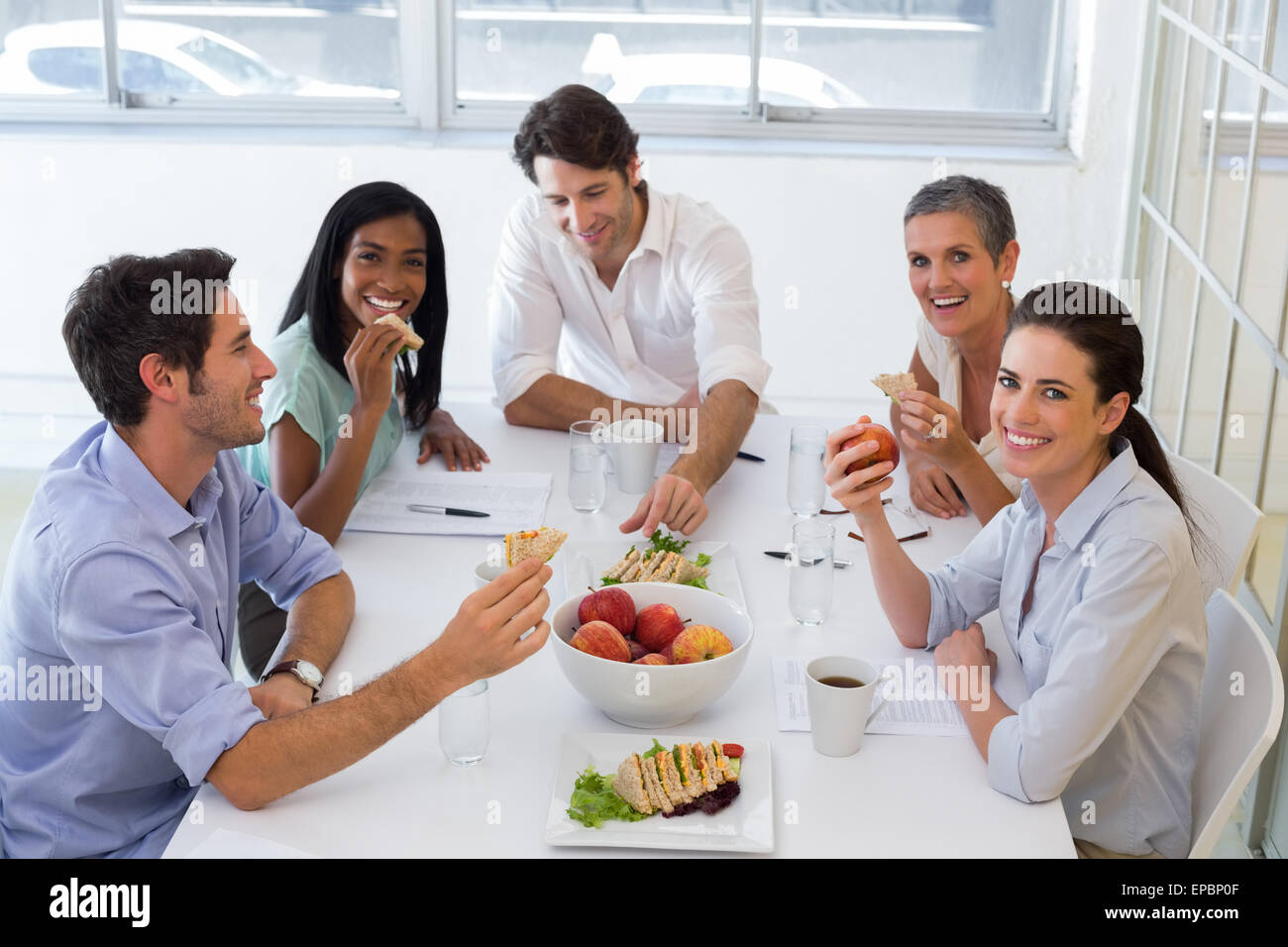 Lavoratori ridere mentre mangiando panini per il pranzo Foto Stock