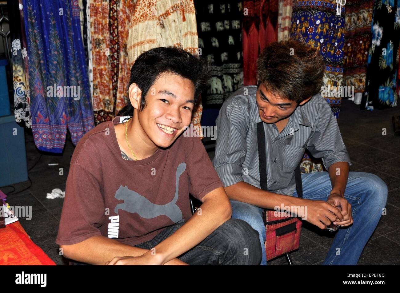 Bangkok, Thailandia: due giovani tailandesi seduto davanti a un marciapiede negozio di abbigliamento su Ratchadamri Road Foto Stock