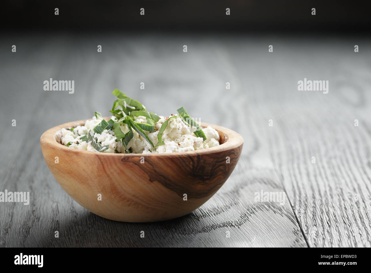 Ricotta fresca con erbe in legno d'olivo ciotola sul vecchio tavolo Foto Stock