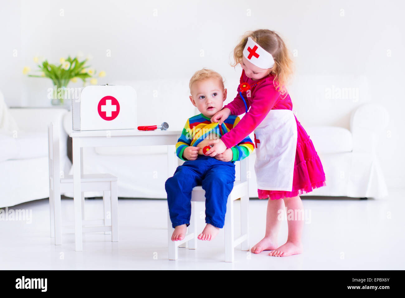 Due bambini felici, cute toddler girl e baby boy, fratello e sorella, riproduzione medico e l'ospedale utilizzando uno stetoscopio giocattolo Foto Stock