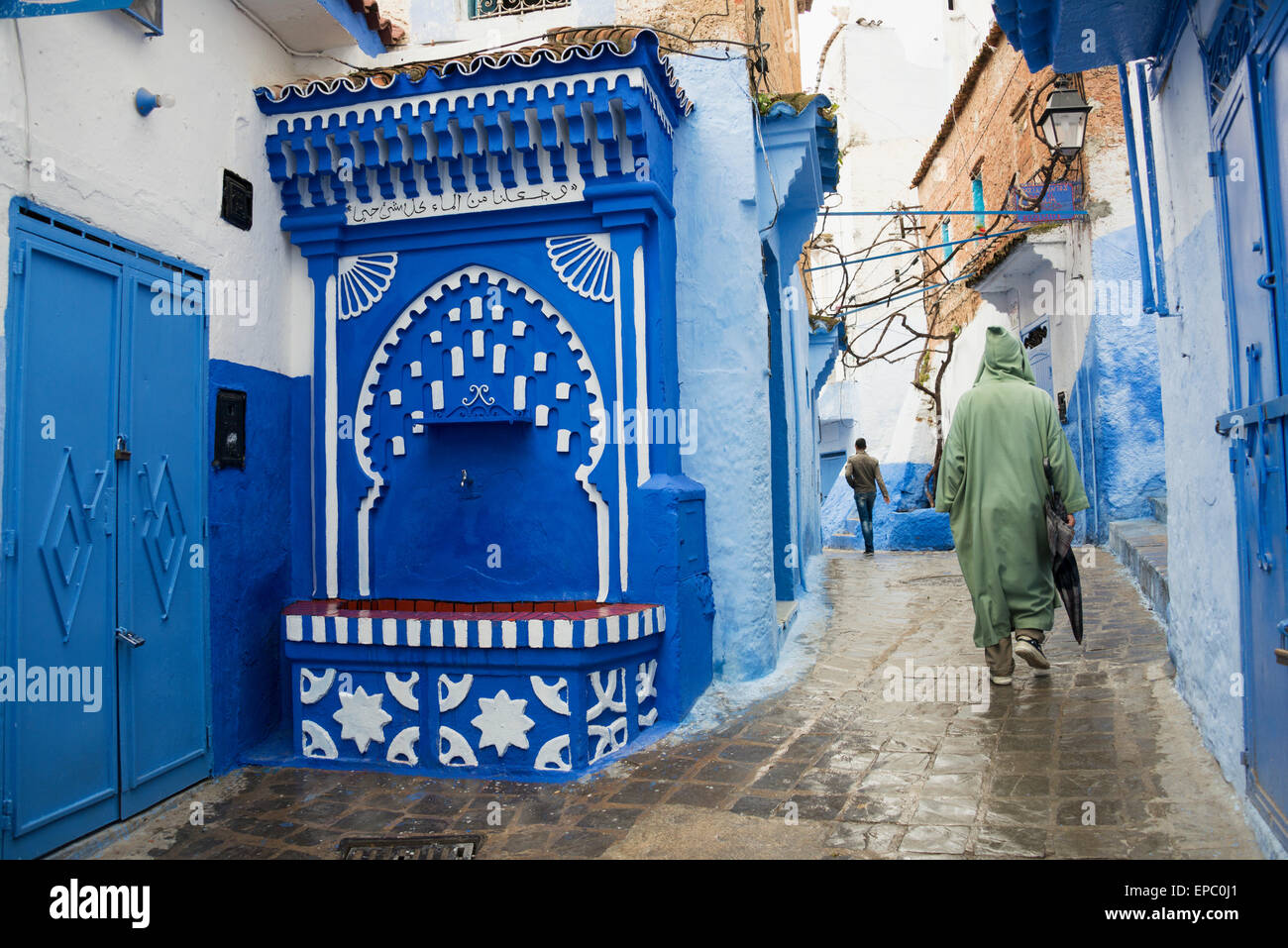 Fontana di acqua con arco islamica in scena di strada; Chefchaouen, Marocco Foto Stock