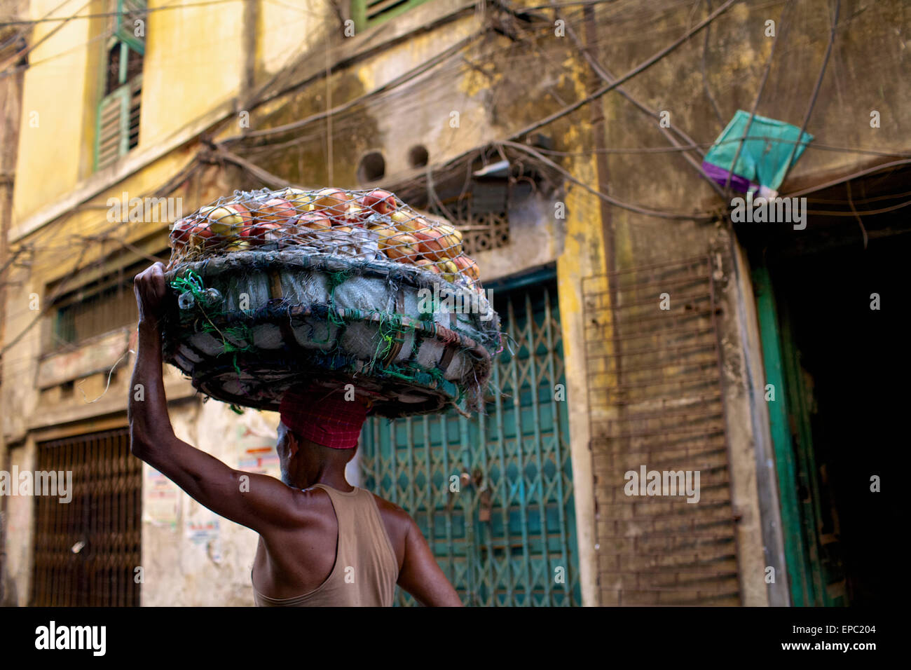 Uomo che porta frutto in un cestello sul suo capo; Kolkata, West Bengal, India Foto Stock