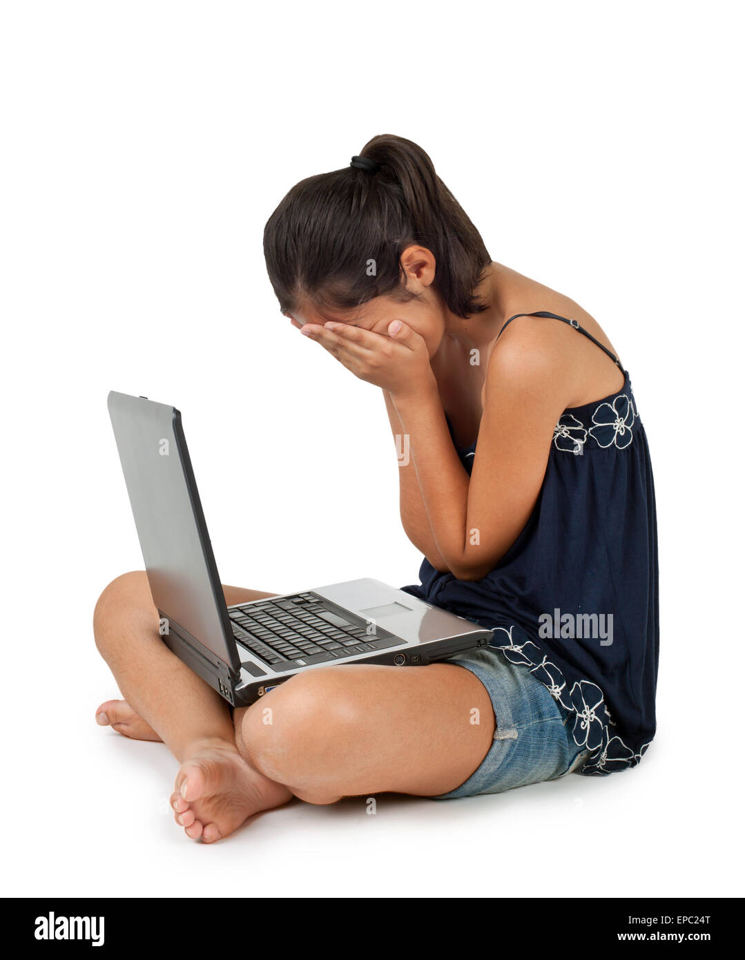 Giovane ragazza adolescente a piangere davanti al portatile su sfondo bianco. Foto Stock