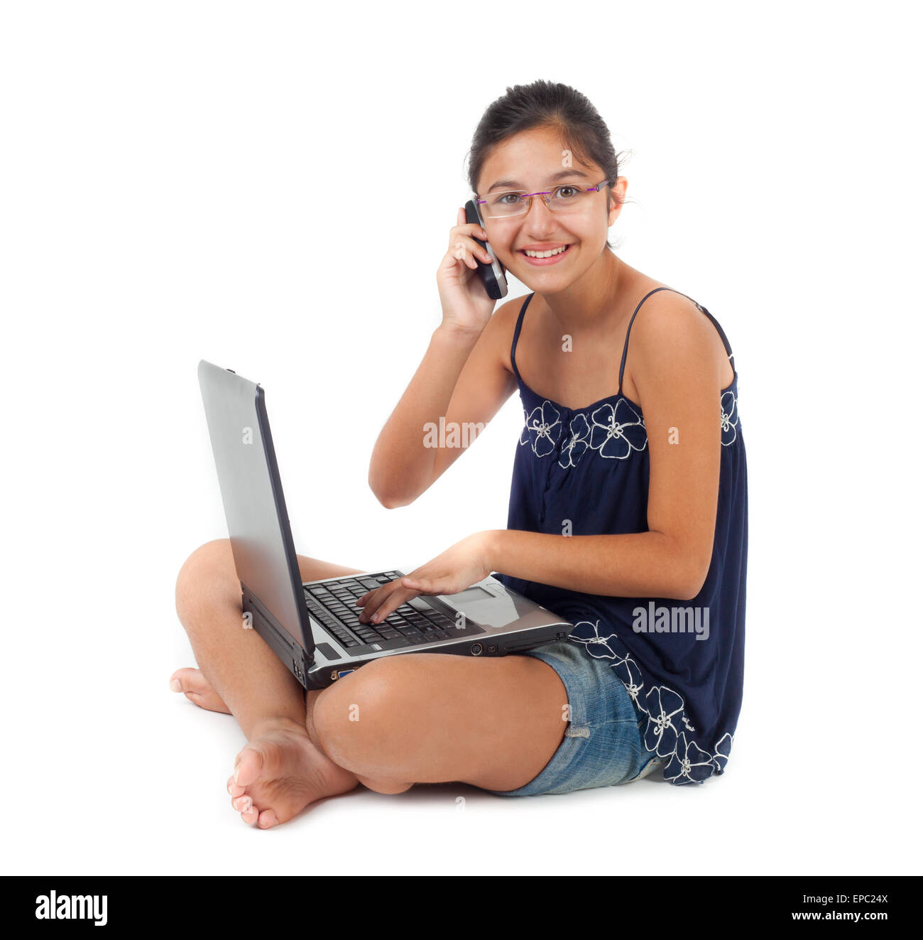 Adolescente mentre si parla al telefono con il notebook sulle gambe. Foto Stock