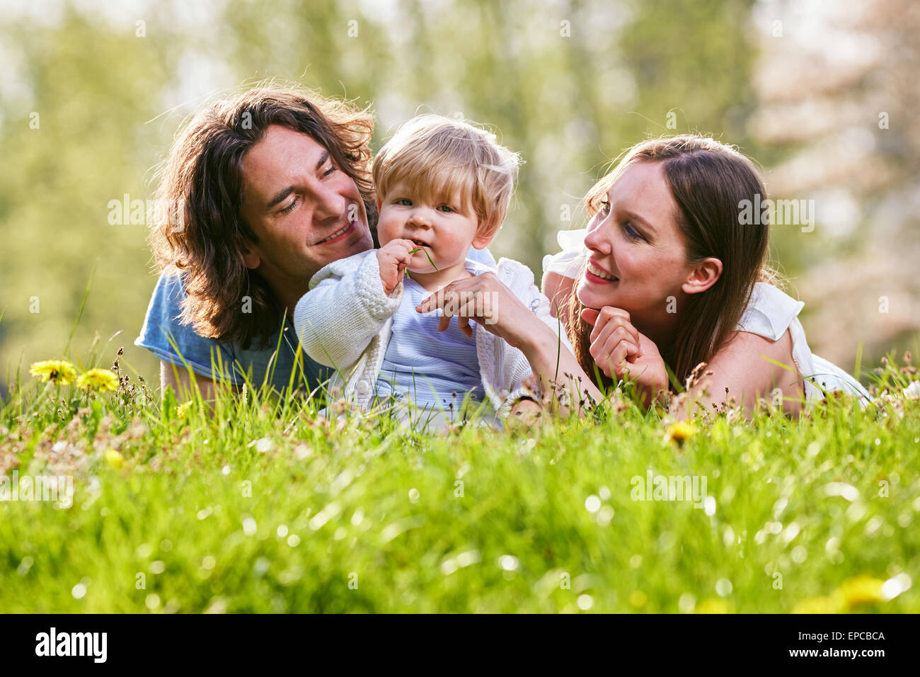 Famiglia giovane insieme in erba sul prato Foto Stock
