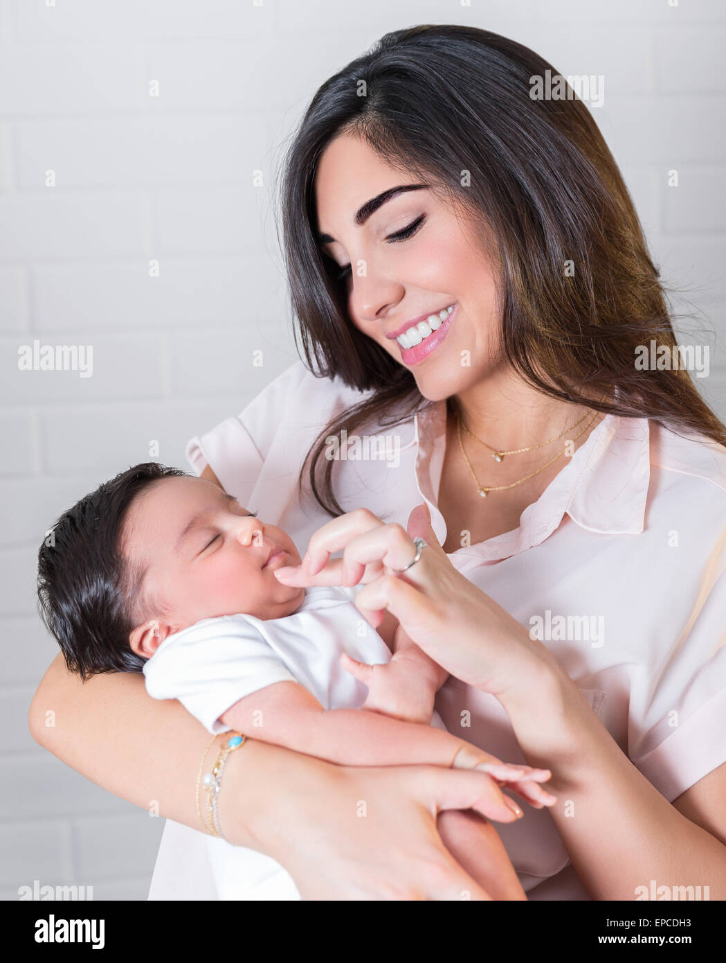 Ritratto di felice madre tenendo le mani sul piccolo grazioso neonato, divertendosi a casa, godendo di maternità, di amore e di felicità Foto Stock