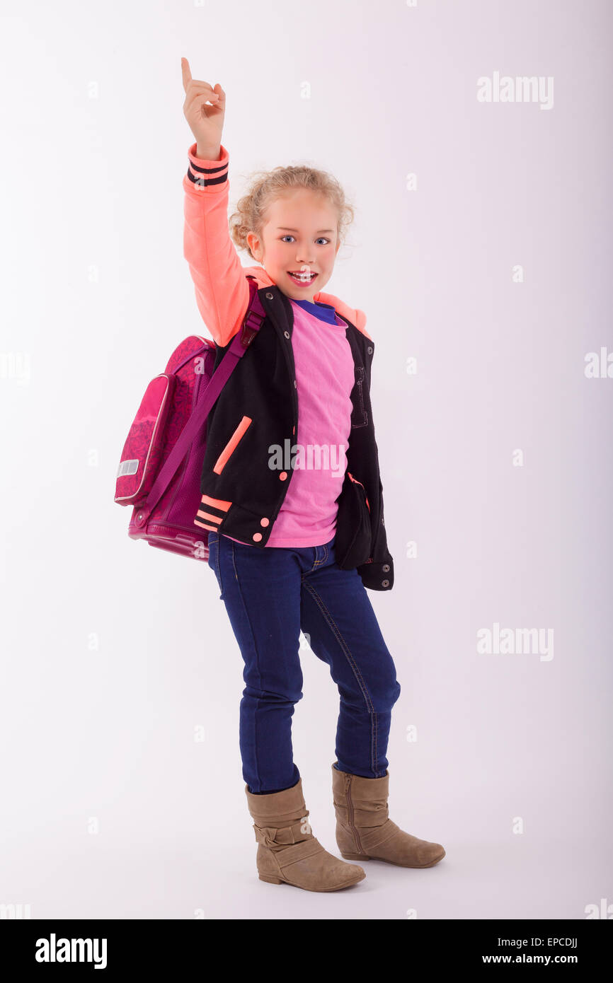 Blonde piccola ragazza con la scuola borsa sul retro, punti con il dito in aria Foto Stock