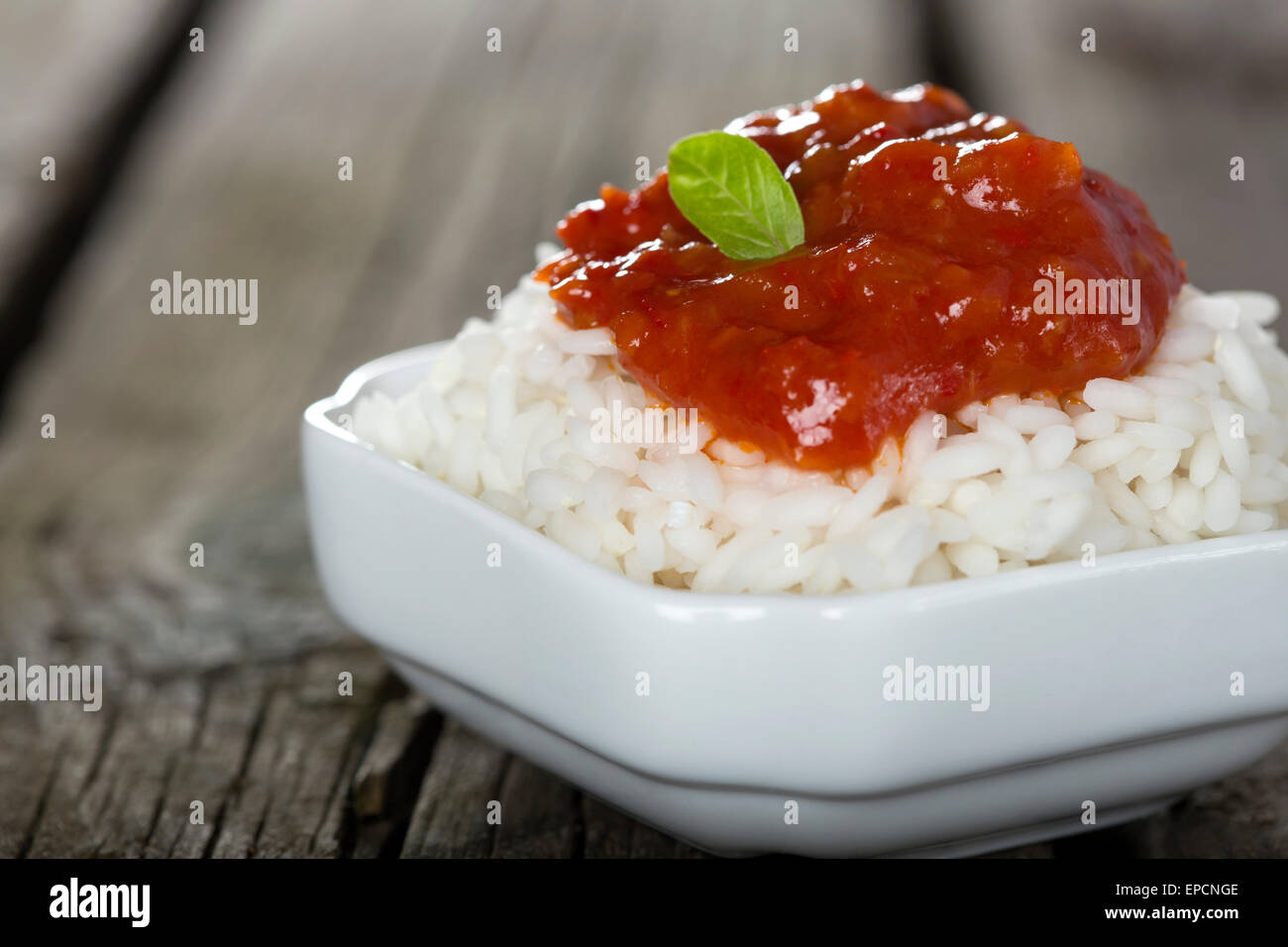 Ciotola di riso e salsa di pomodoro su sfondo di legno Foto Stock
