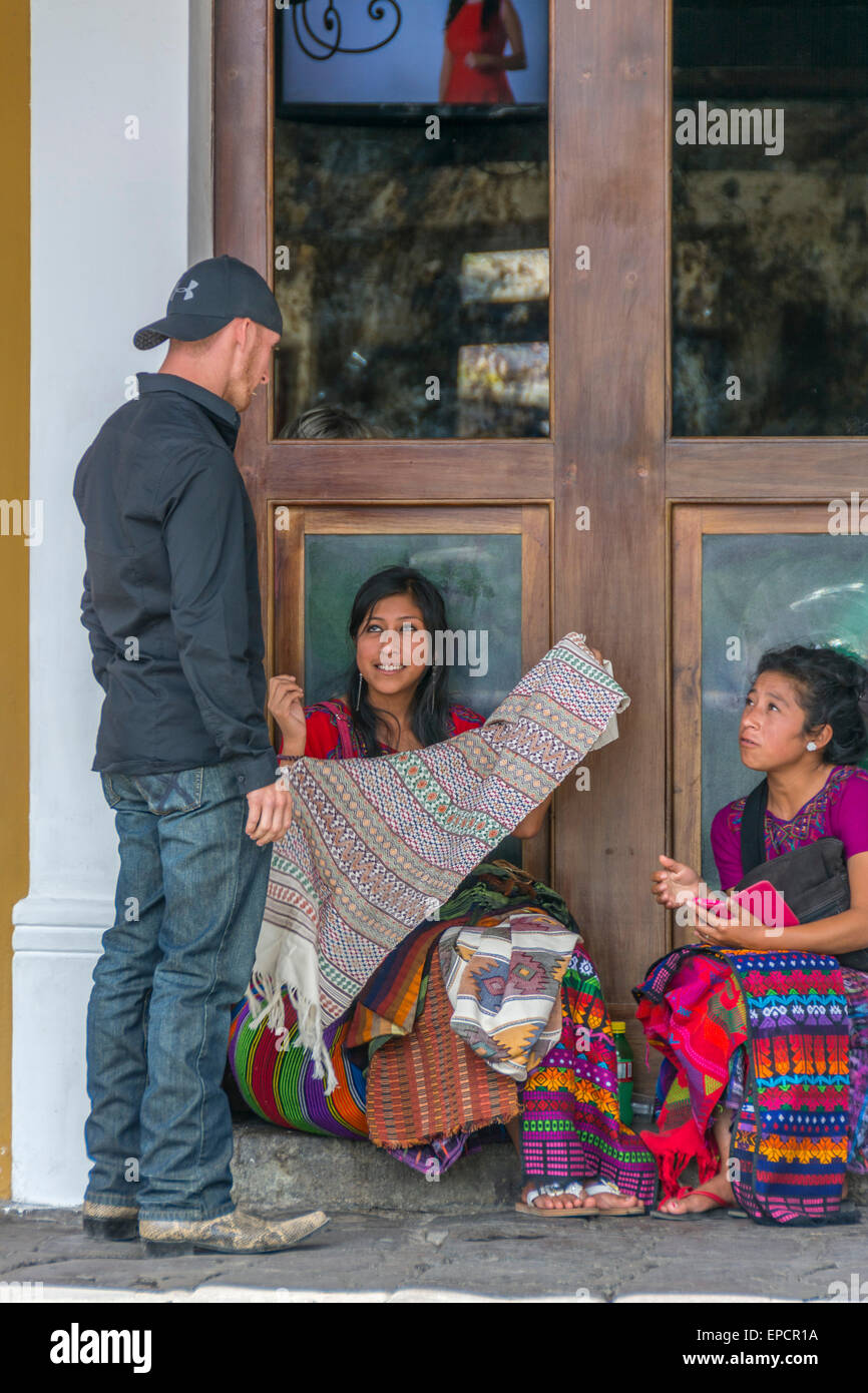 Le donne guatemalteche visualizzazione Myan tradizionali tessuti per la vendita a un americano in Antigua Guatemala. Foto Stock