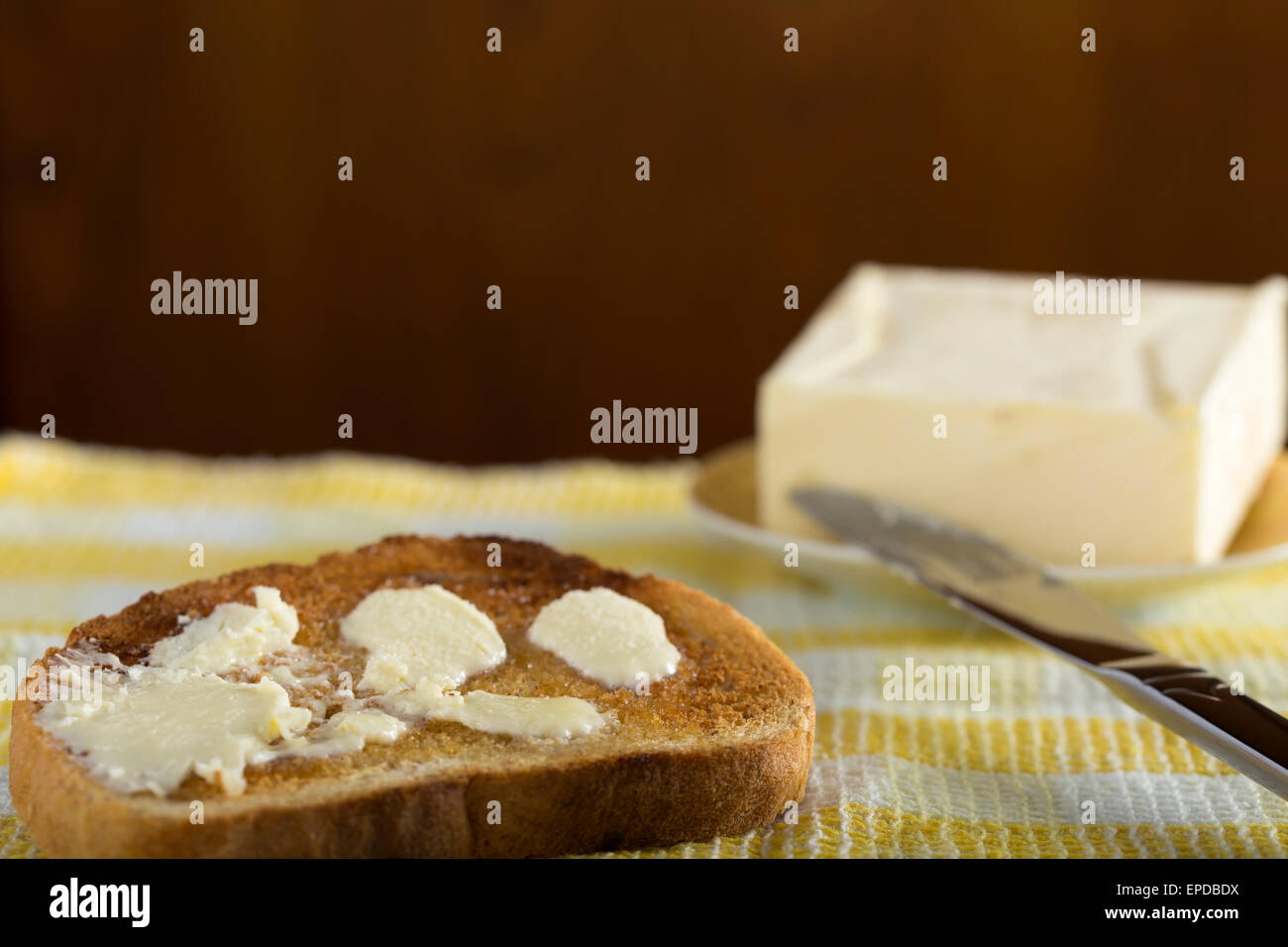 Fetta di bianco toast imburrato su una piastra e coltello Foto Stock