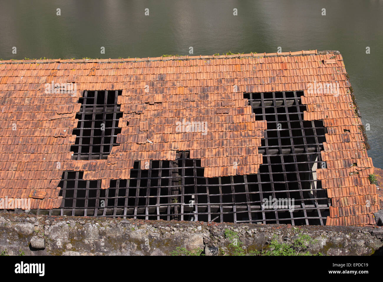 Foro danneggiato nel tetto di tegole con telaio in legno di un edificio tradizionale. Foto Stock