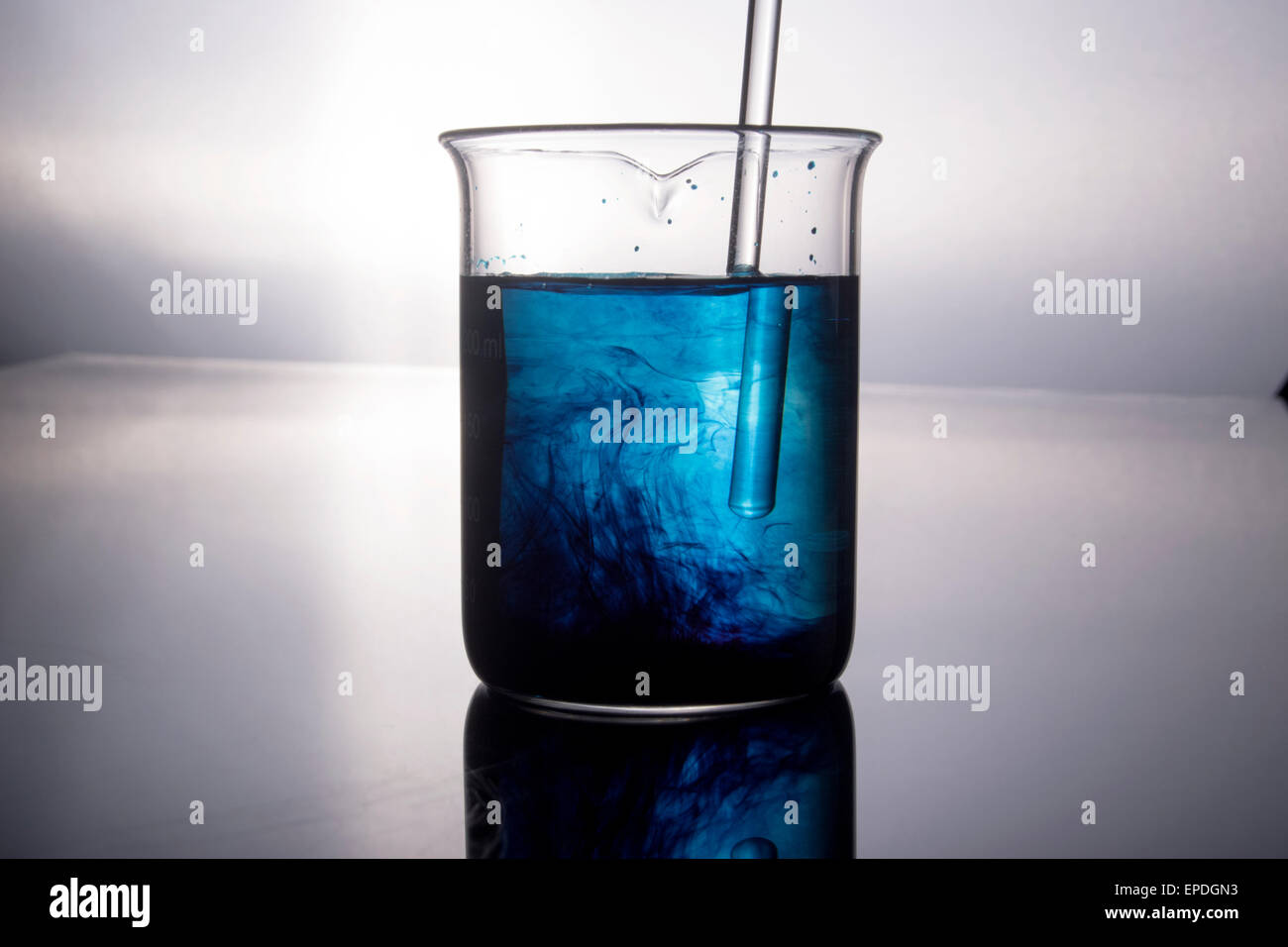 Becher con la chimica blu viene agitato con la bacchetta di vetro Foto Stock
