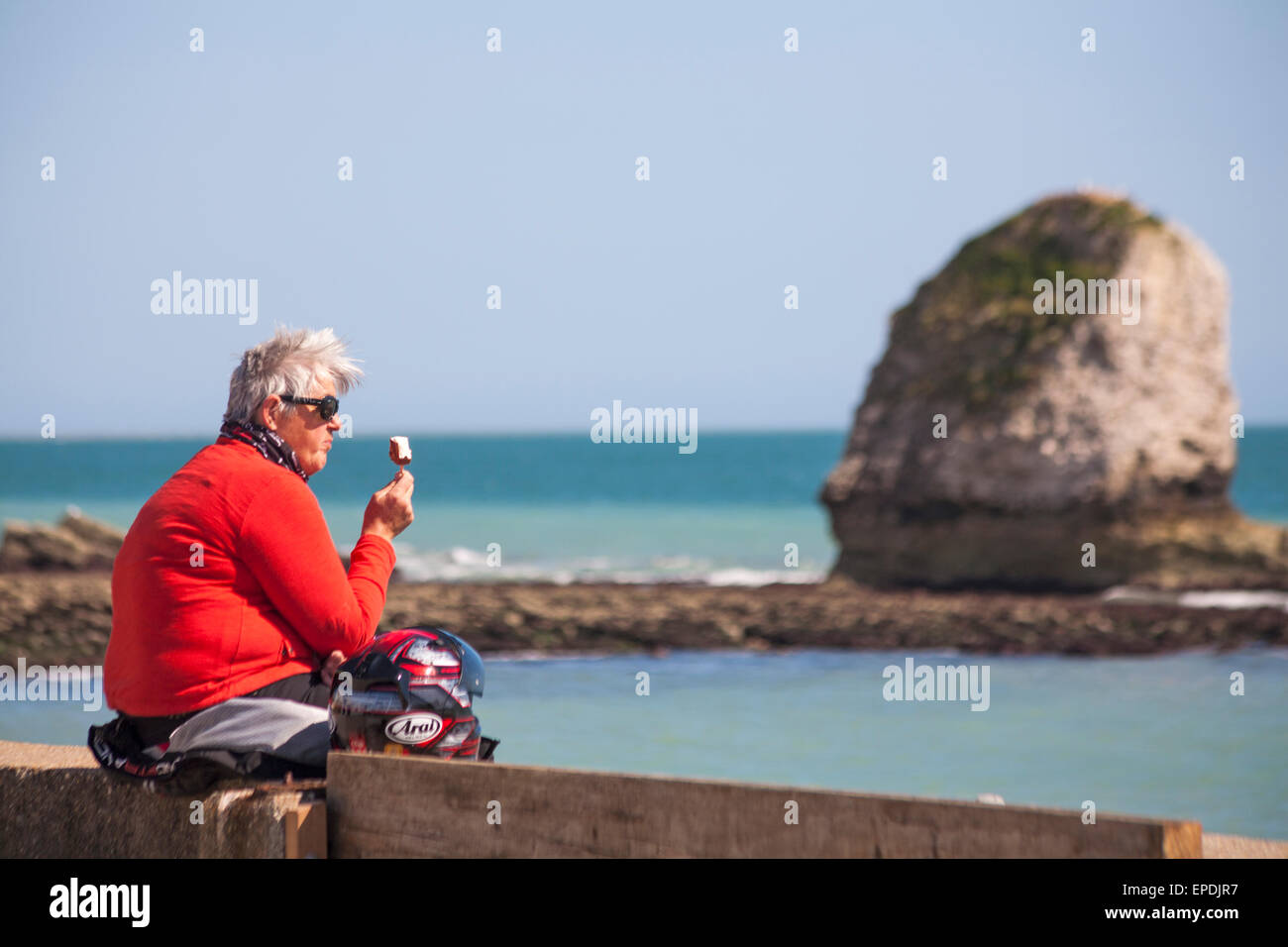 Donna seduta godendo il sole e gelato presso la baia di acqua dolce, Isle of Wight, Hampshire REGNO UNITO NEL MESE DI MAGGIO Foto Stock