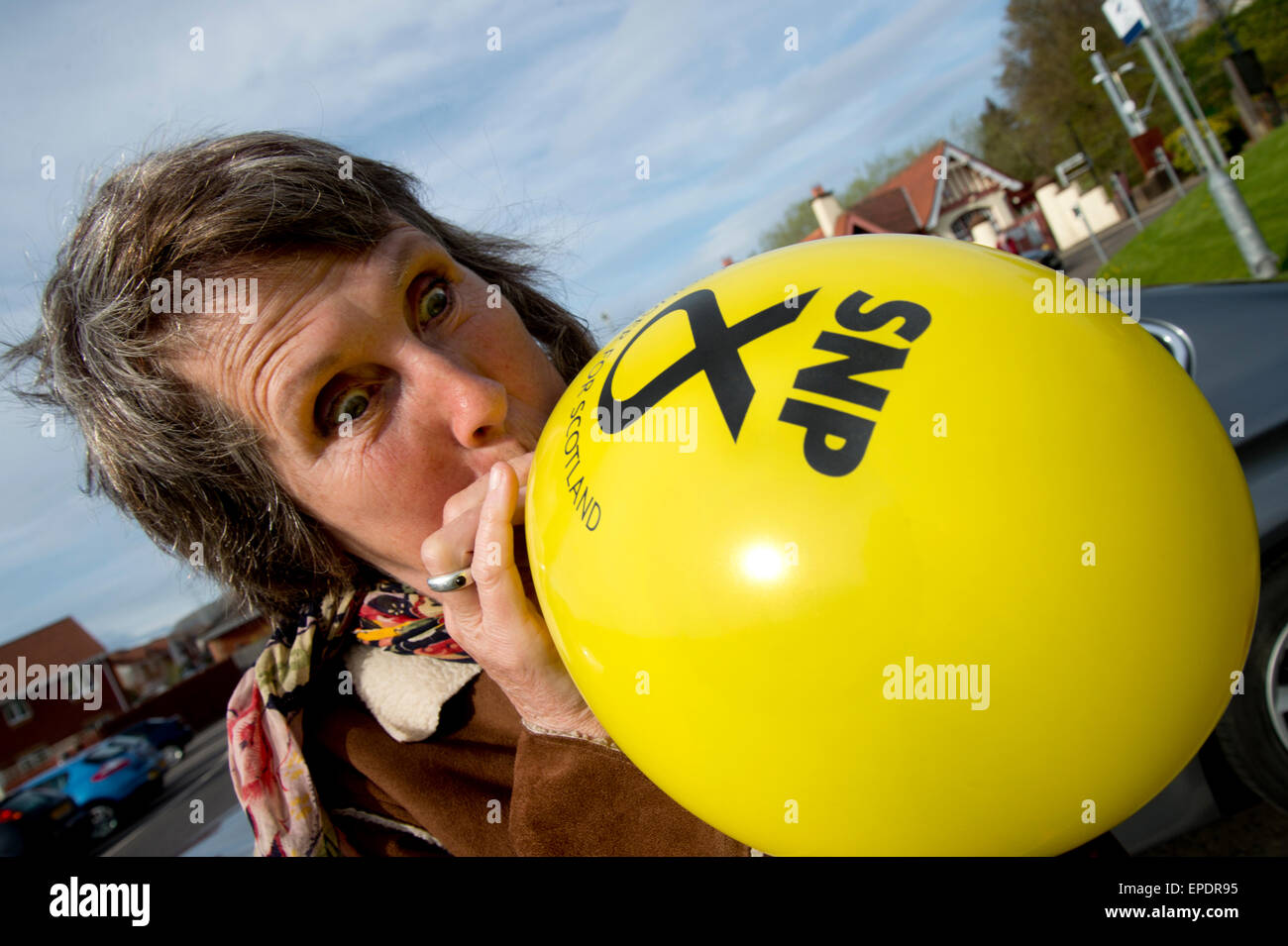 Un sostenitore del SNP (Partito nazionale scozzese) soffia su un palloncino prima di prendere parte a una vigilia di elezione cavalcata. Foto Stock