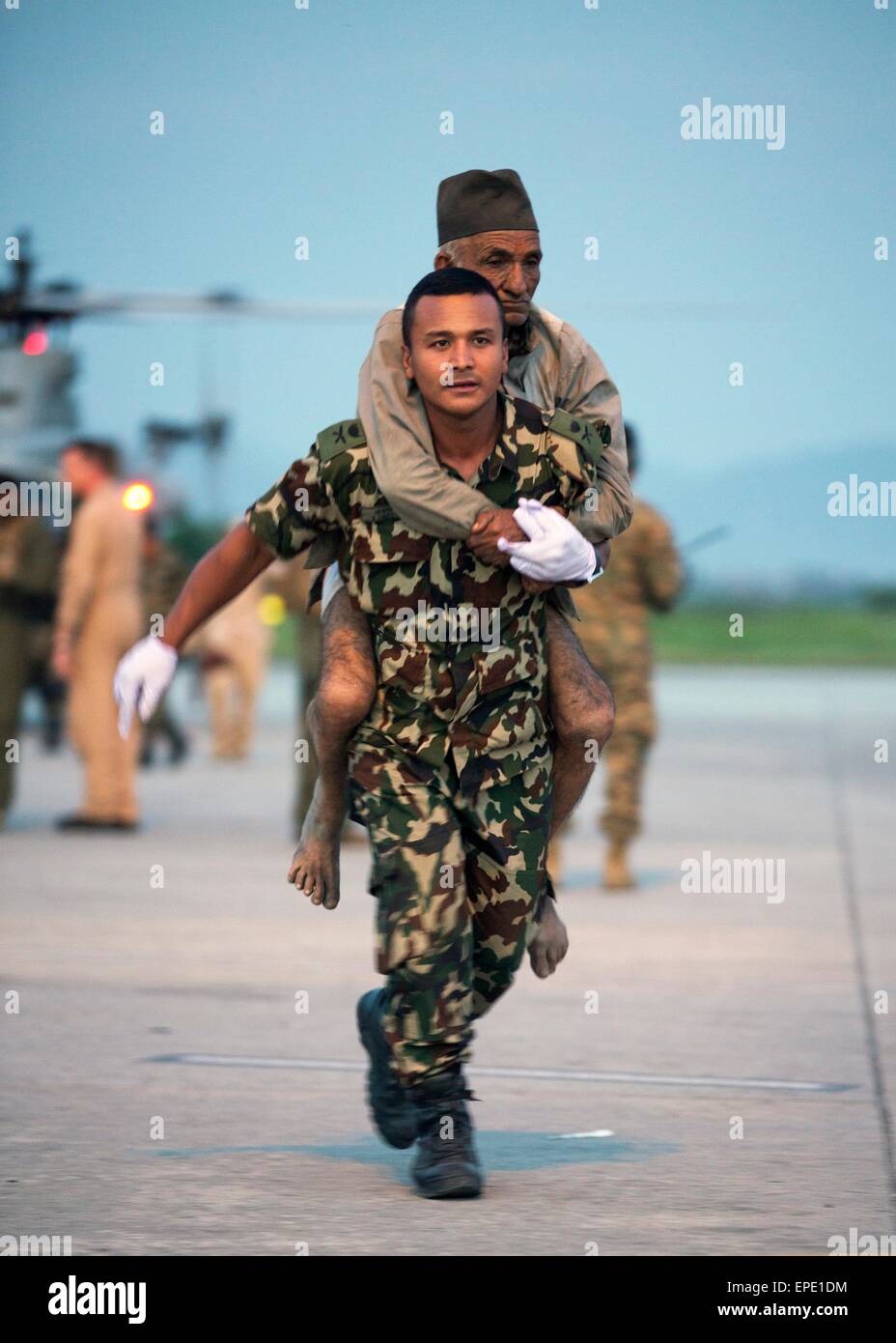 Un soldato Nepalese porta un uomo ferito al medico area di triage presso l'aeroporto internazionale di Tribhuvan Maggio 12, 2015 a Kathmandu, Nepal. Un 7.3 grandezza aftershock terremoto ha colpito il regno a seguito del 7.8 terremoto di magnitudine su Aprile 25th. Foto Stock