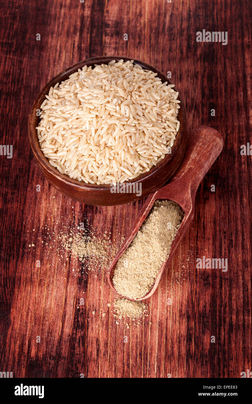 Riso tondo in ciotola di legno con riso dietetica fibra sul cucchiaio di legno in legno marrone scuro e sfondo, vista dall'alto. Mangiare sano Foto Stock