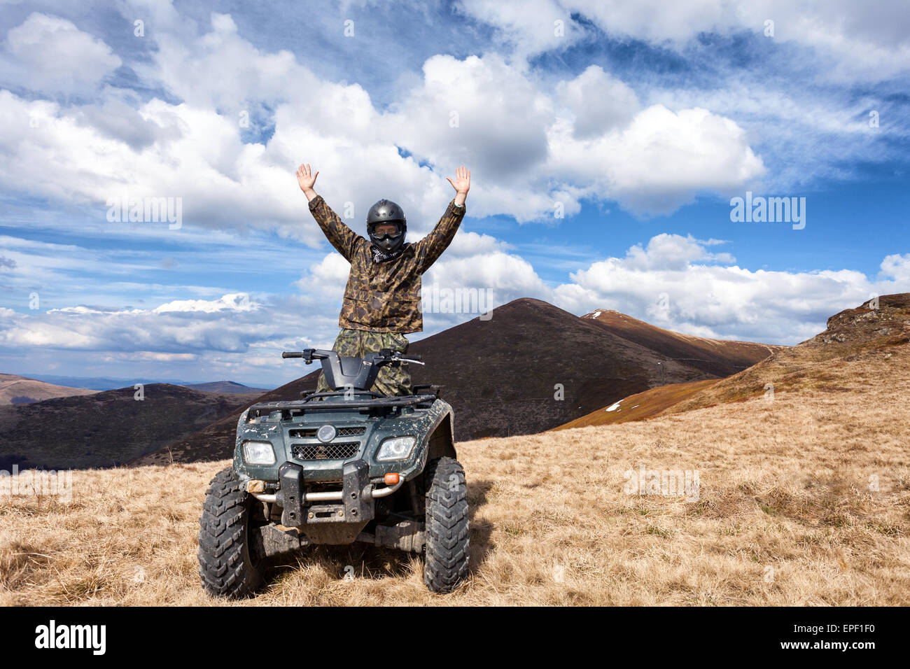 Il pilota maschio su ATV alla cima della montagna Foto Stock