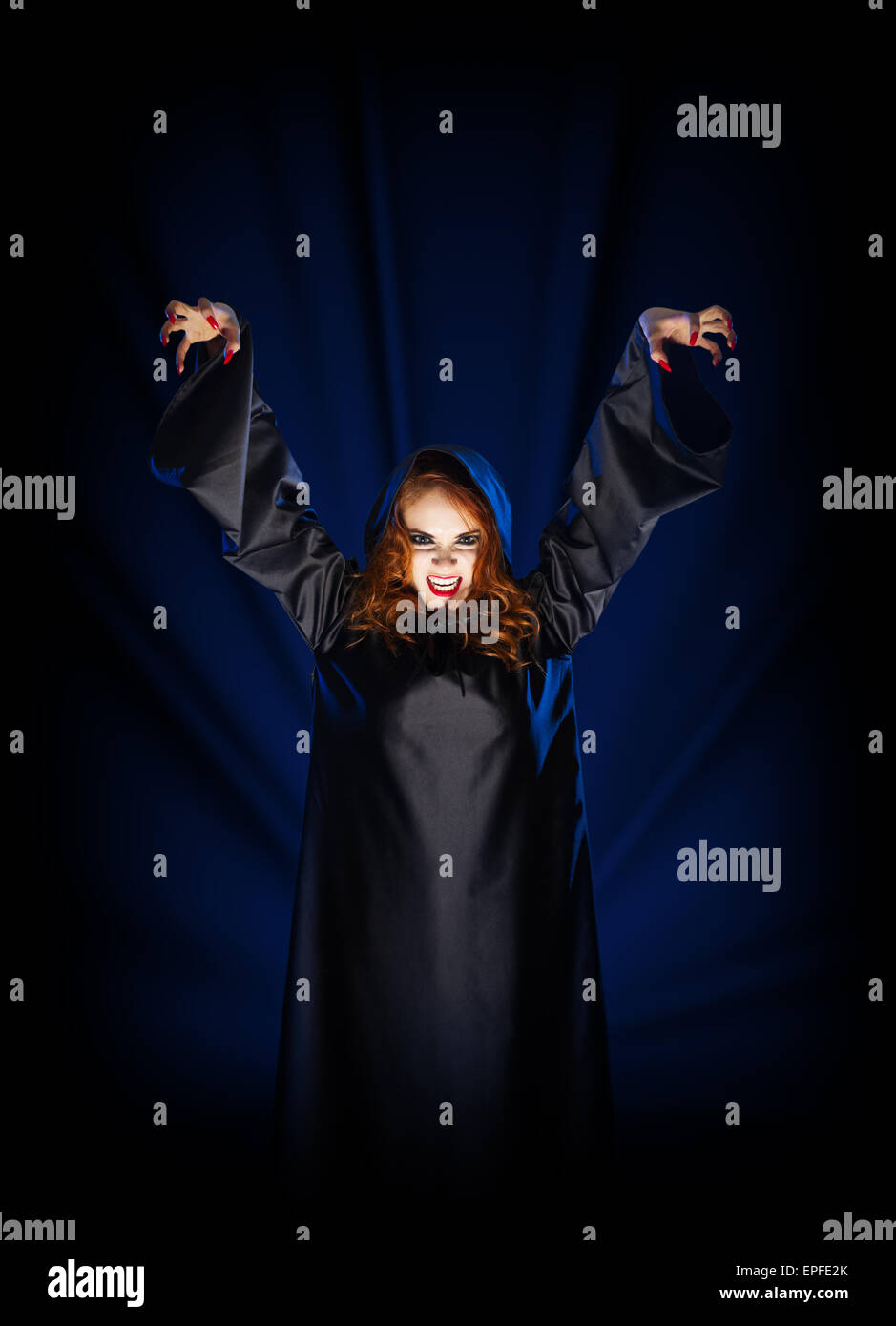 Giovane ragazza strega su blu raggi di luce sullo sfondo Foto Stock