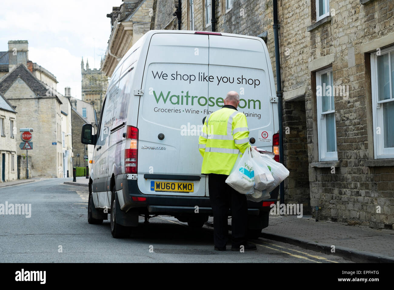 Un Waitrose consegna a domicilio del lavoratore conducente furgone portando un carrello per un cliente a Cirencester, Gloucestershire, England Regno Unito Foto Stock