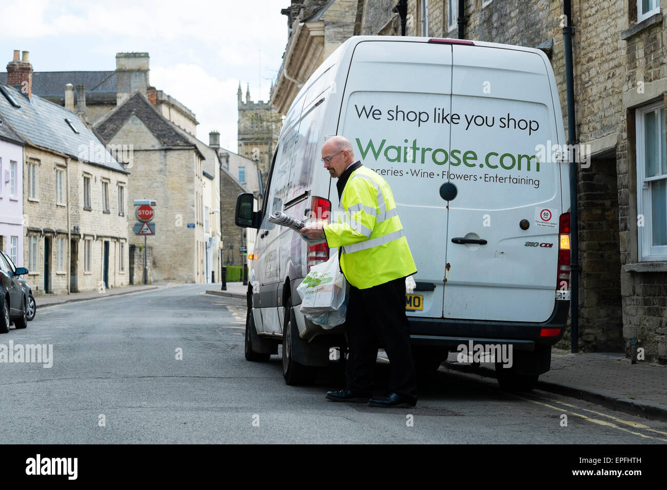 Un Waitrose (Waitrose.com) home delivery lavoratore portando un carrello per un cliente a Cirencester, Gloucestershire, England Regno Unito Foto Stock