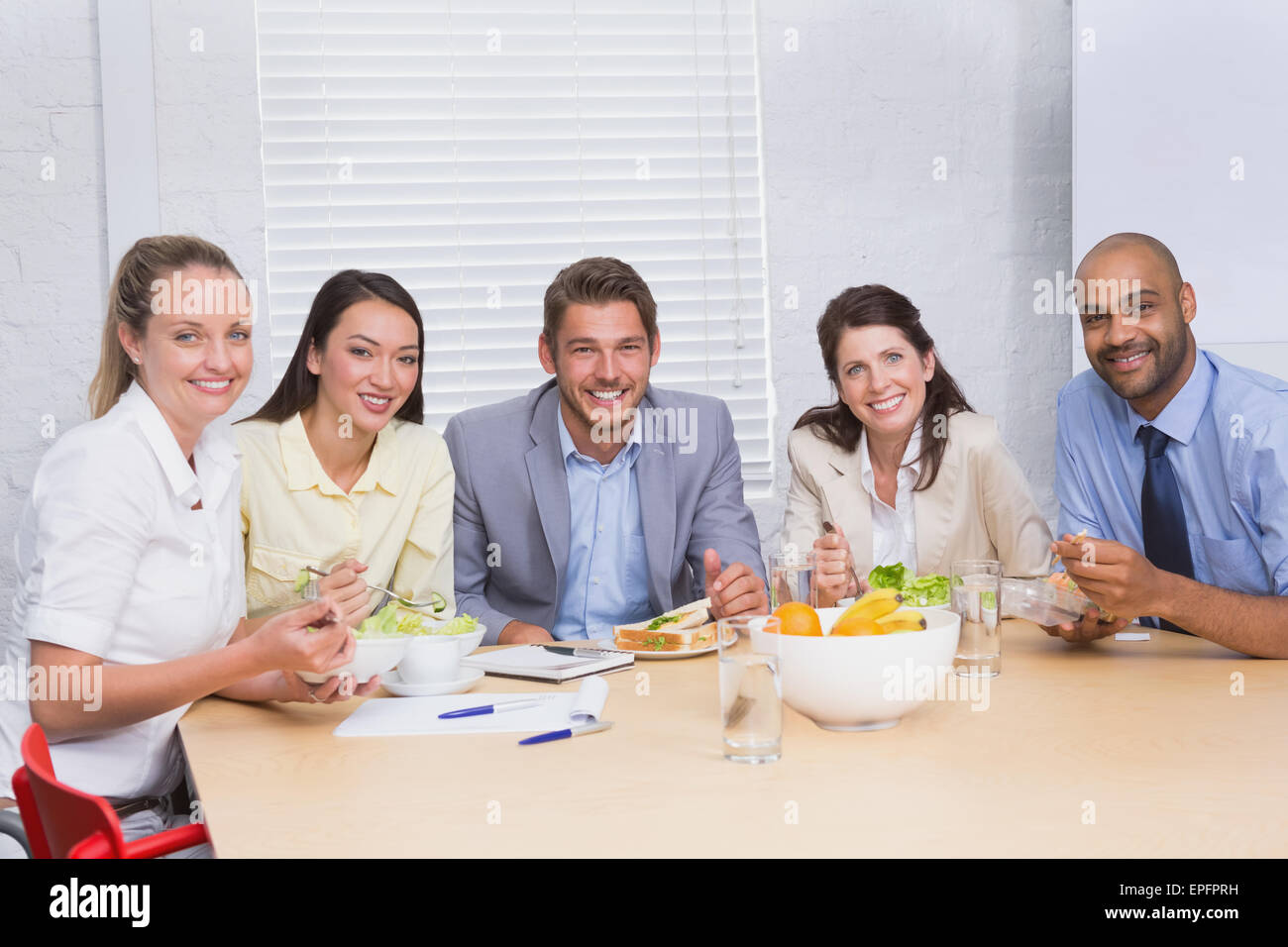 Lavoratori sorridente in telecamera mangiando panini e insalata mista Foto Stock