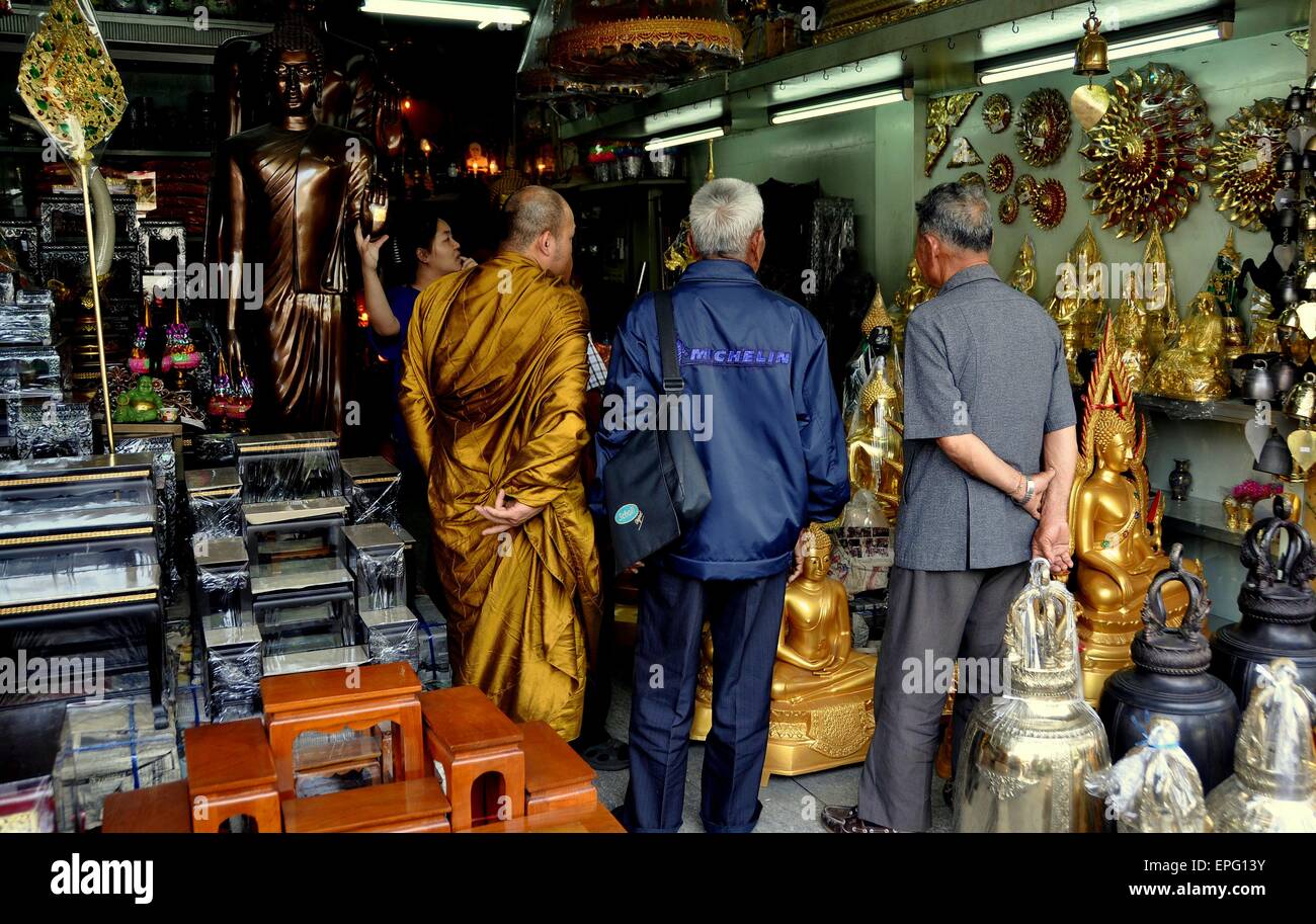 Bangkok, Thailandia: un monaco con due uomini Thai shopping in un negozio specializzato in oggetti religiosi su Thanon Bamrung Muang Foto Stock