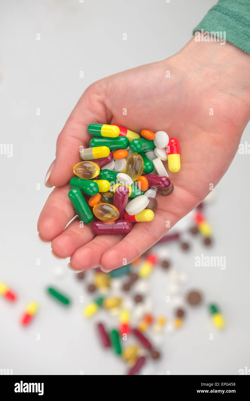 Molte pillole di colore in mano Foto Stock