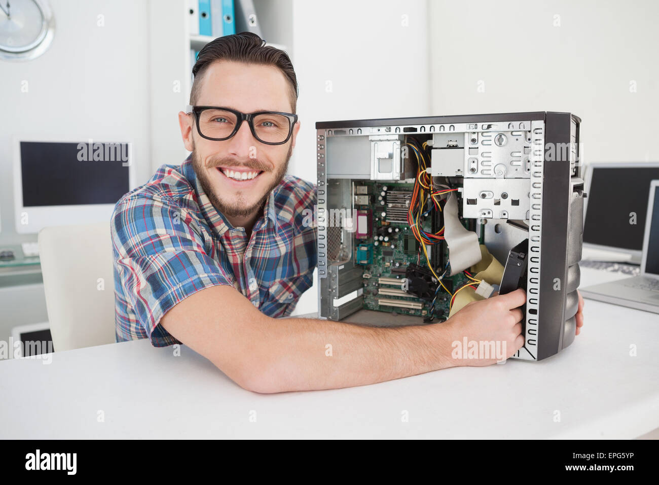 Ingegnere Informatico lavorando sulla console rotto sorridente in telecamera Foto Stock